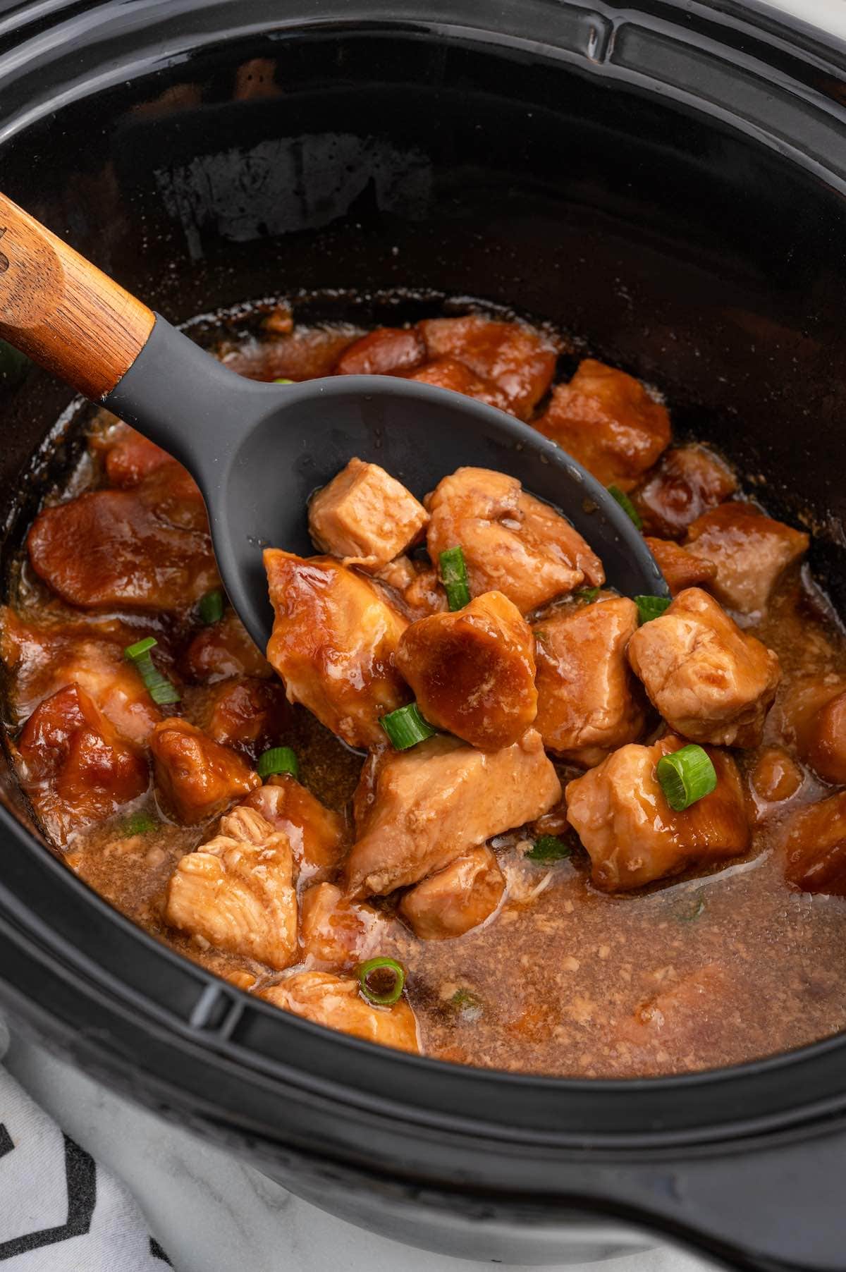 using a ladle to take heaps amount of Sweet Hawaiian Chicken from slow cooker.