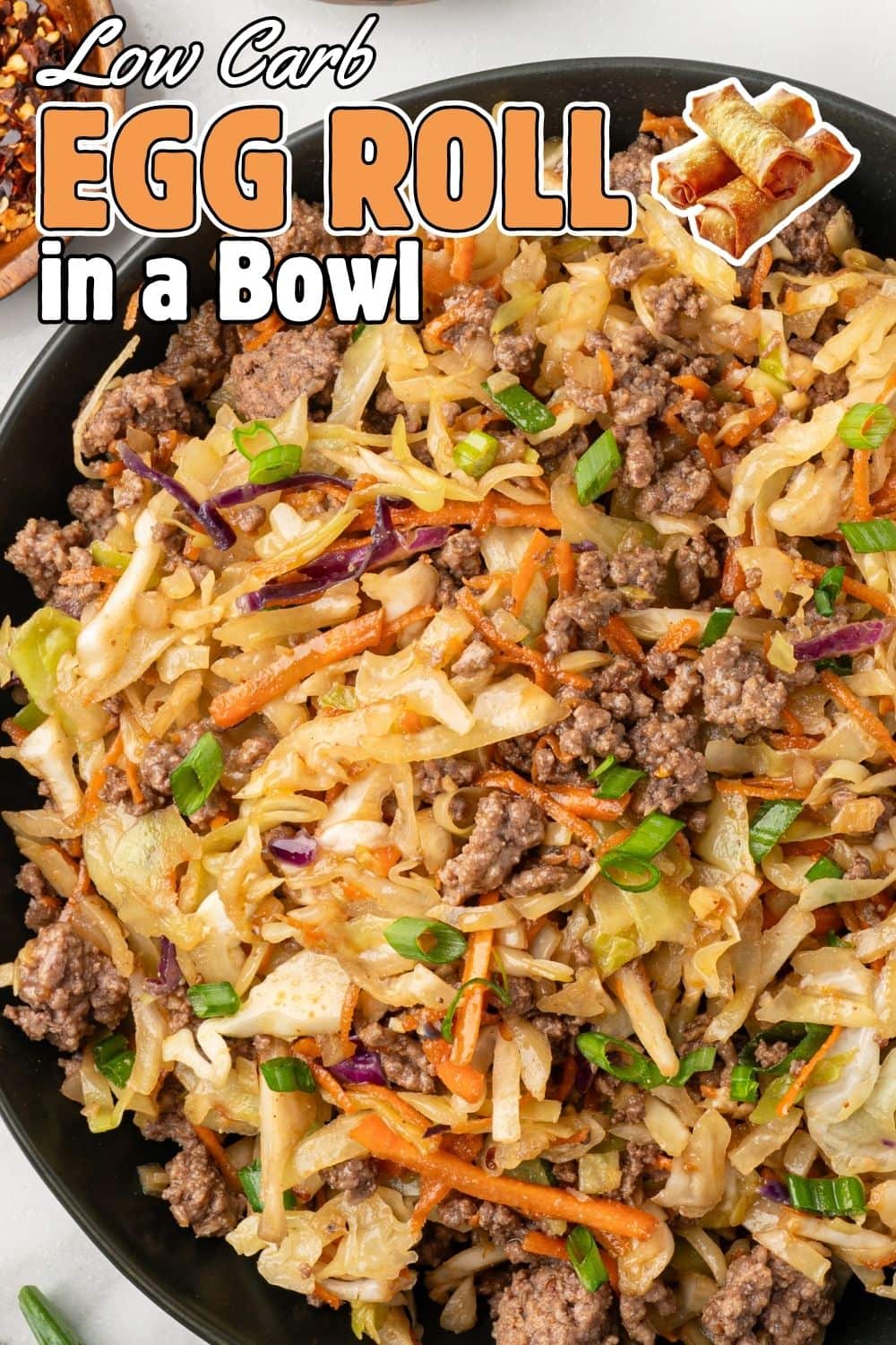 Low Carb Egg Roll in a Bowl with ground beef, cabbage, shredded carrots, and green onions in a dark skillet.