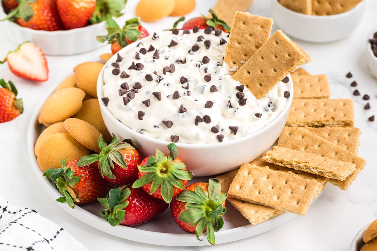 a bowl of Booty Dip with crackers and strawberries on the side.