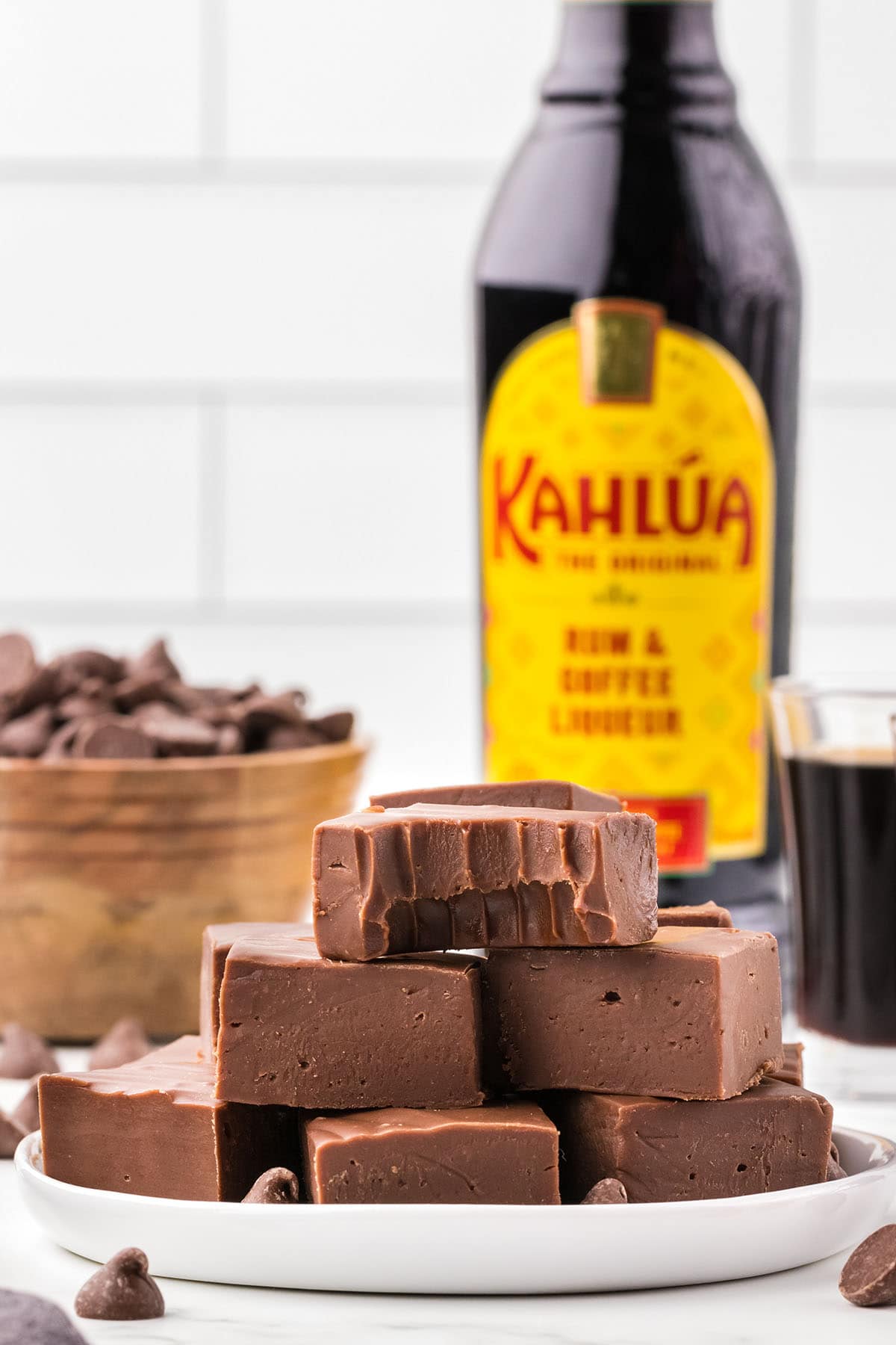 a couple of Kahlua Fudge on the plate with a bottle of Kahlua in the background.