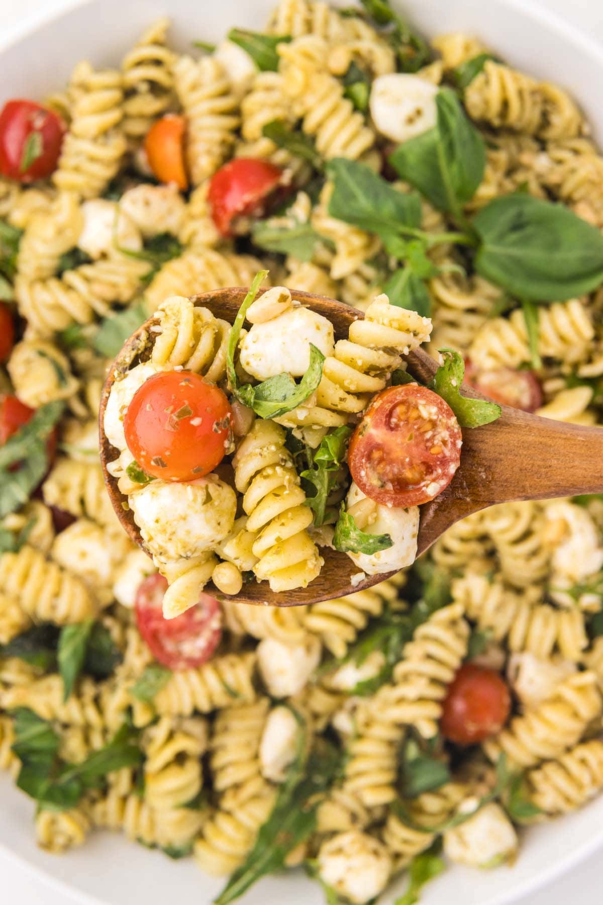 a spoonful of Pesto Pasta Salad using a wooden spoon.