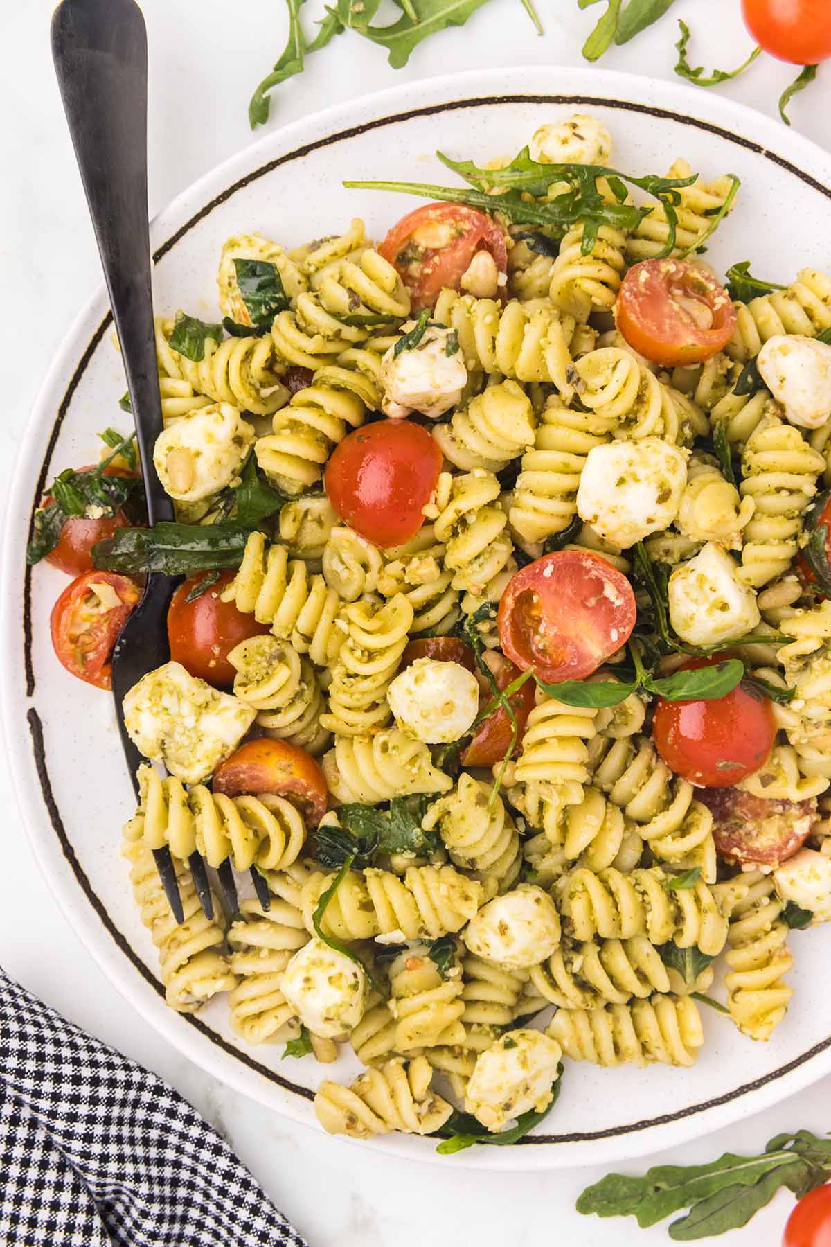 a plate full of pesto pasta salad with fork on it. 