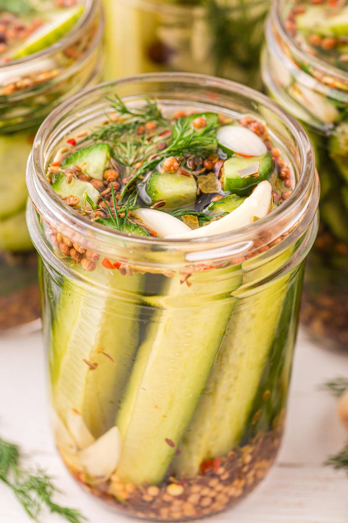 Refrigerator Dill Pickles in a jar with red pepper flakes and garlic on top.