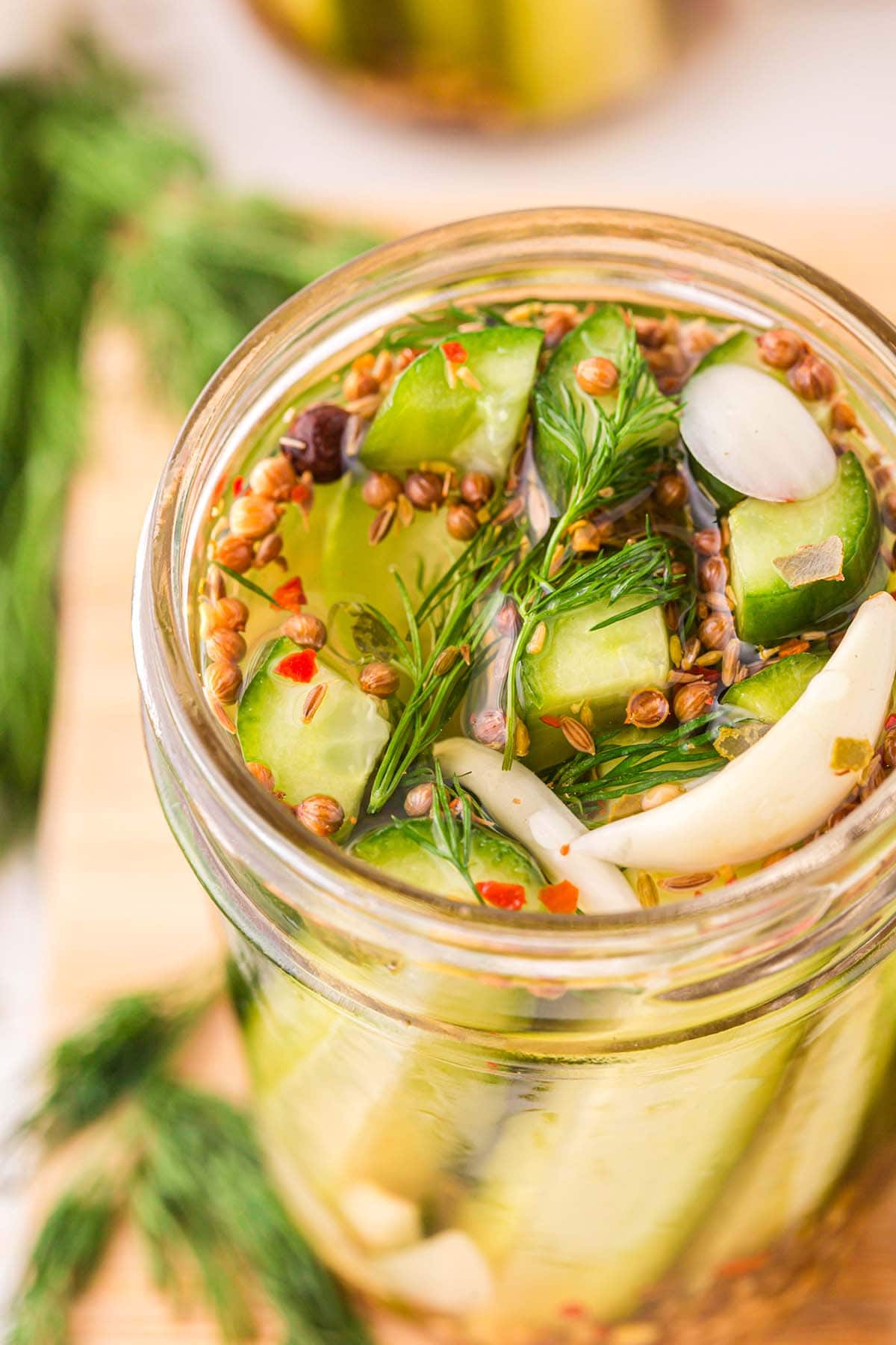 a jar of Refrigerator Dill Pickles with red pepper flakes on top.