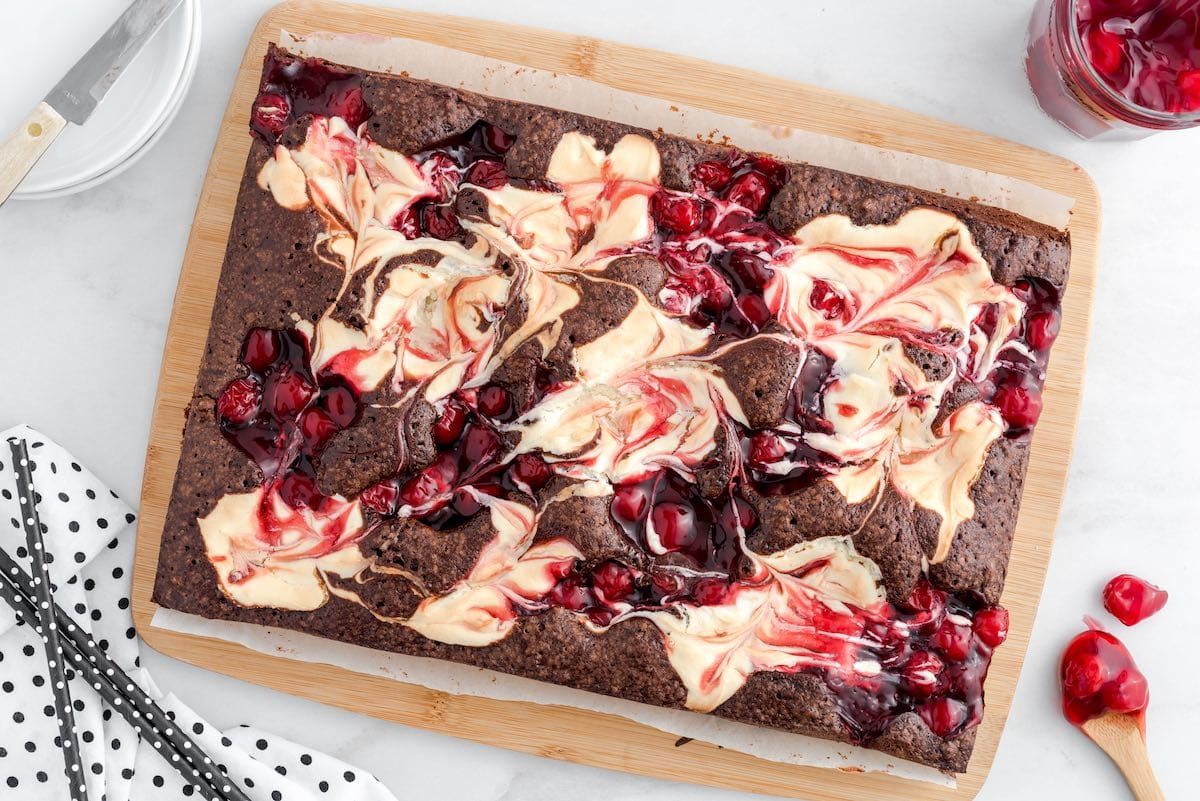 uncut Cherry Cheesecake Brownies on the table with extra cherries on the side.