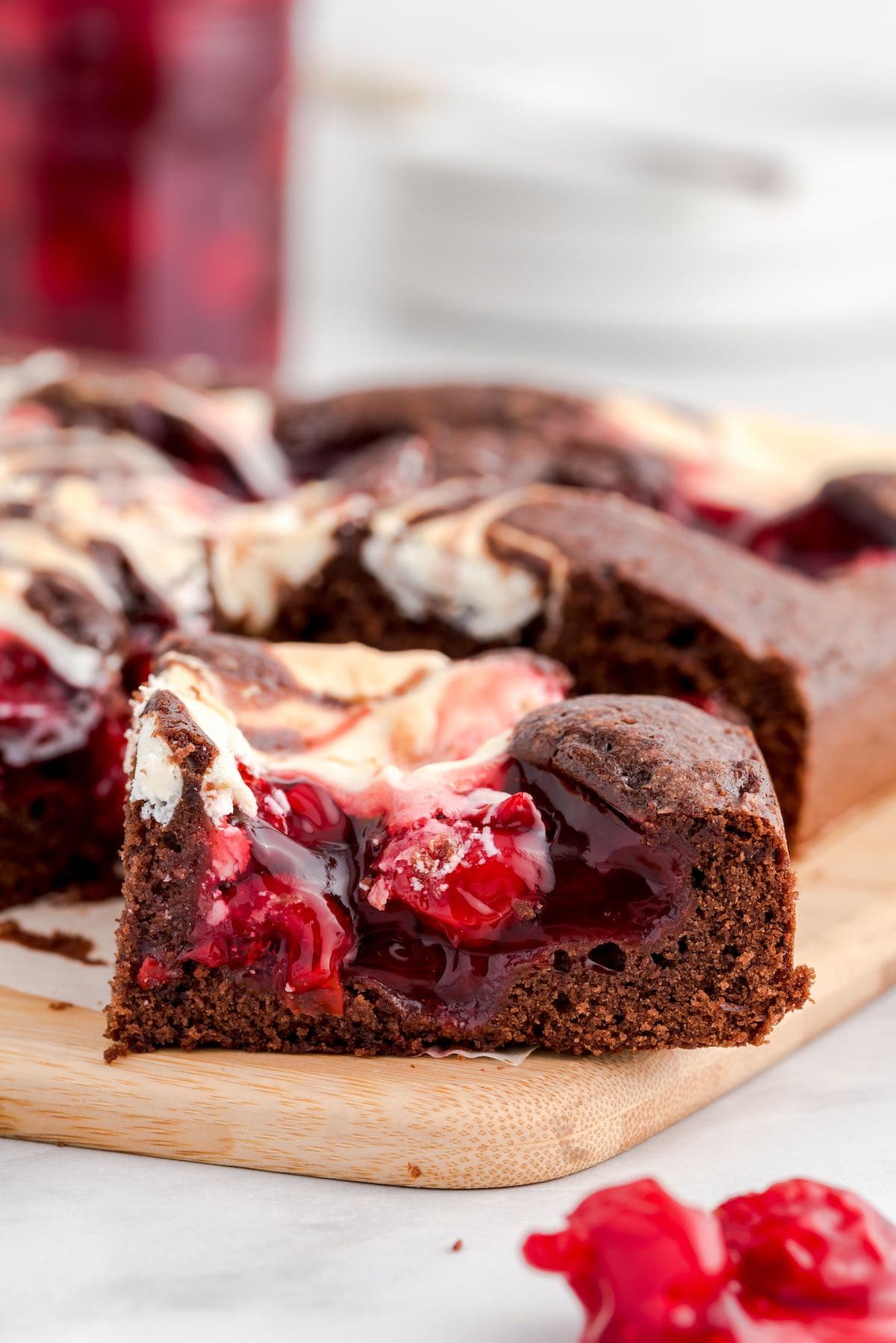 a slice of Cherry Cheesecake Brownies on top of a wooden board.