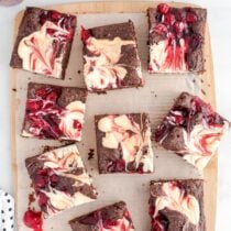 a couple of Cherry Cheesecake Brownies on top of wooden board.