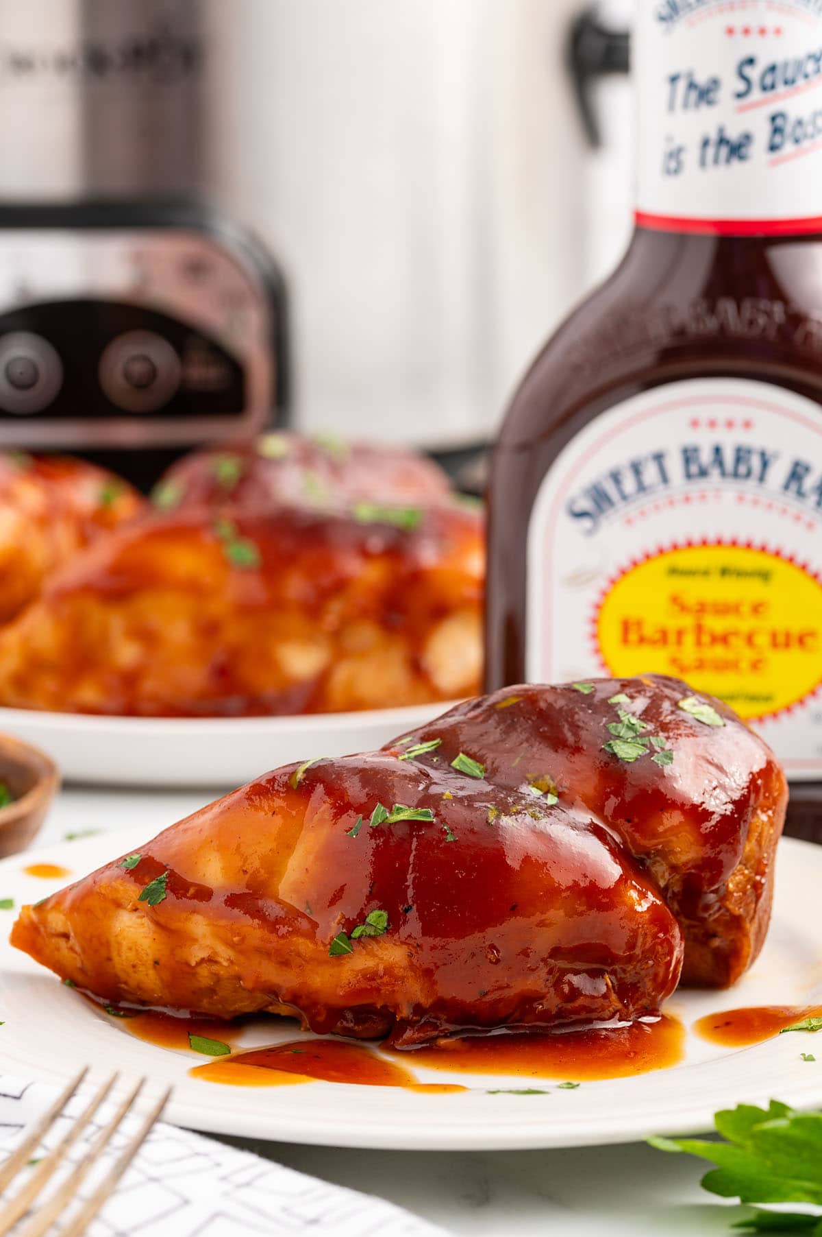barbecue sauce drizzled over Sweet Baby Rays Crockpot Chicken.