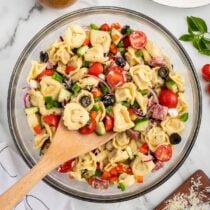 Tortellini Pasta Salad in a large bowl with wooden spoon.