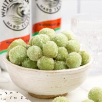 a bowl filled green grapes that are coated in sugar.