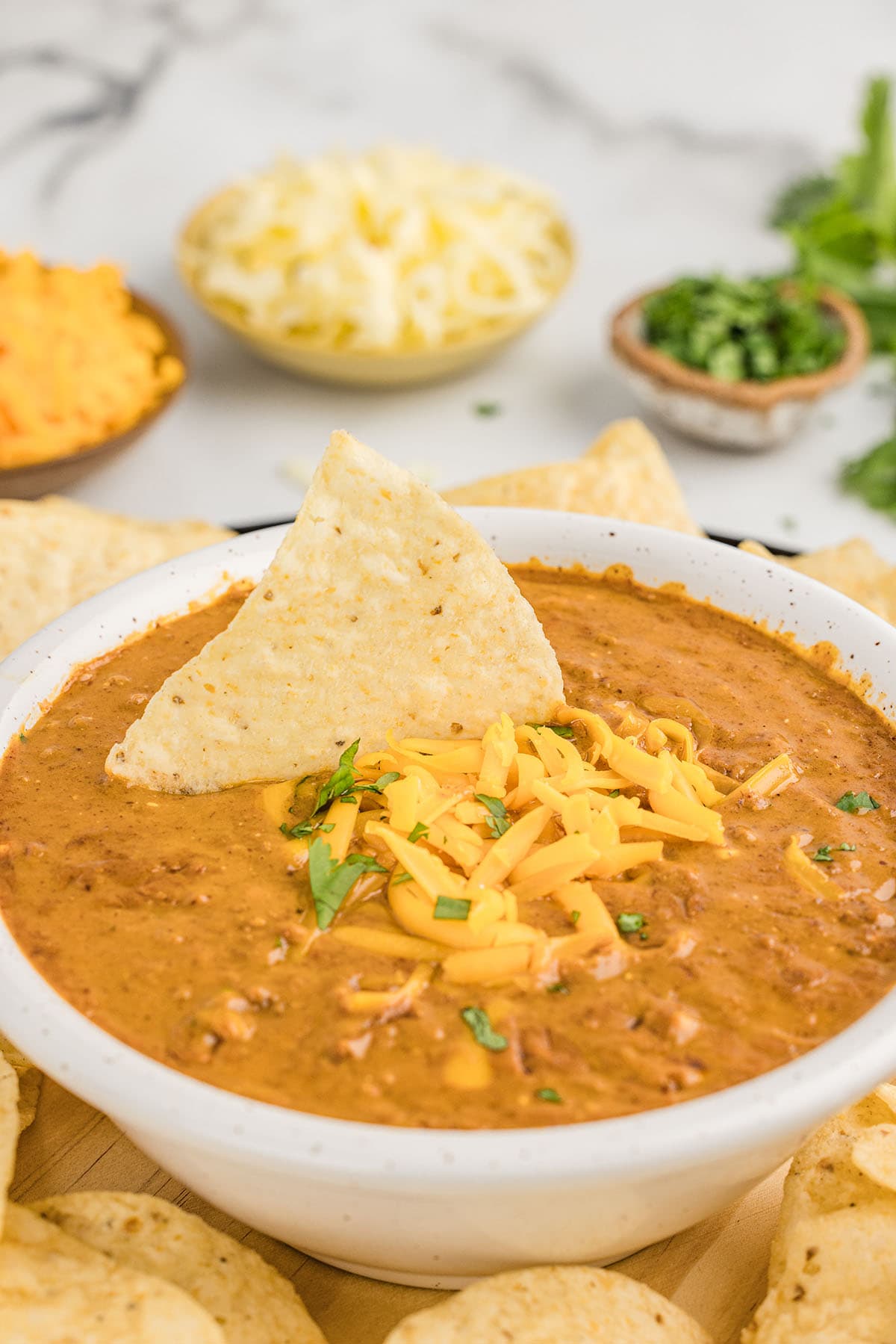 chili cheese dip in a bowl topped with shredded cheese. 