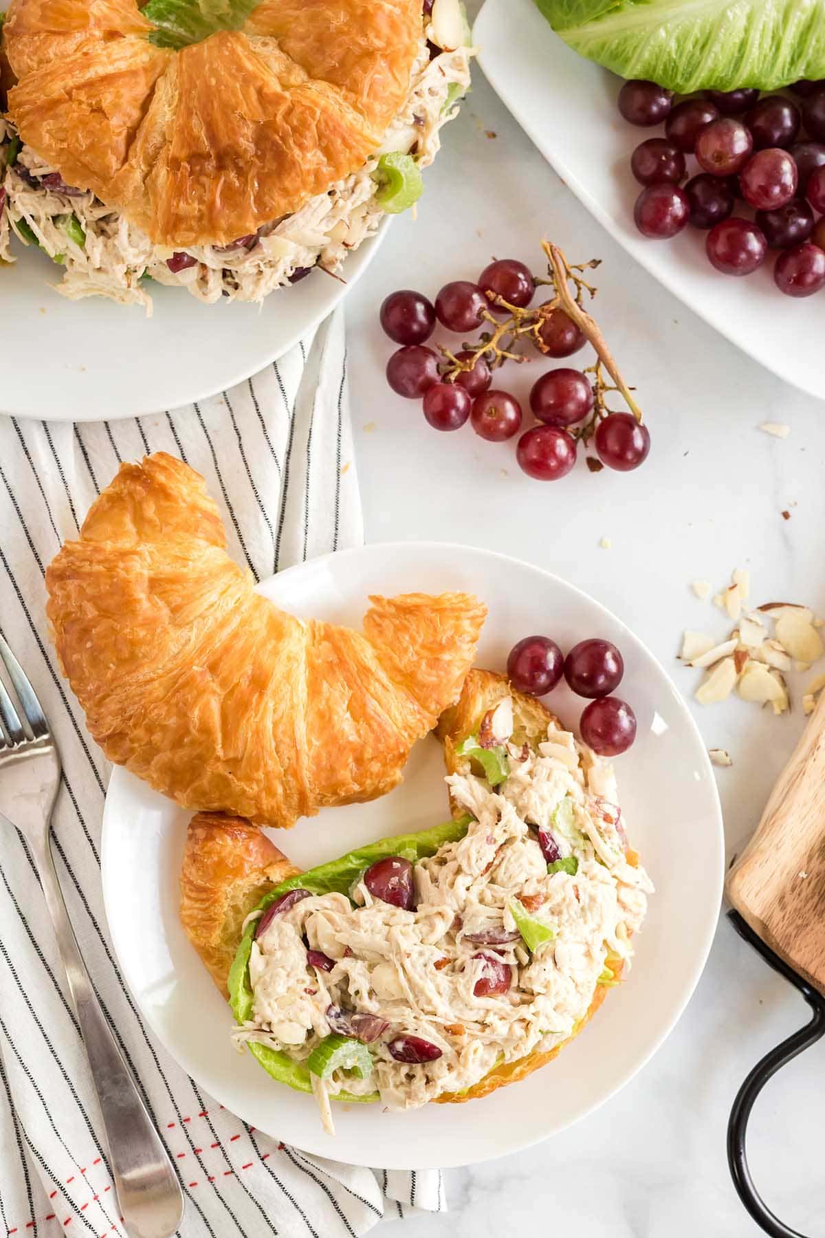 Sandwiches made with croissant filled with Chicken Salad and grapes on the table.