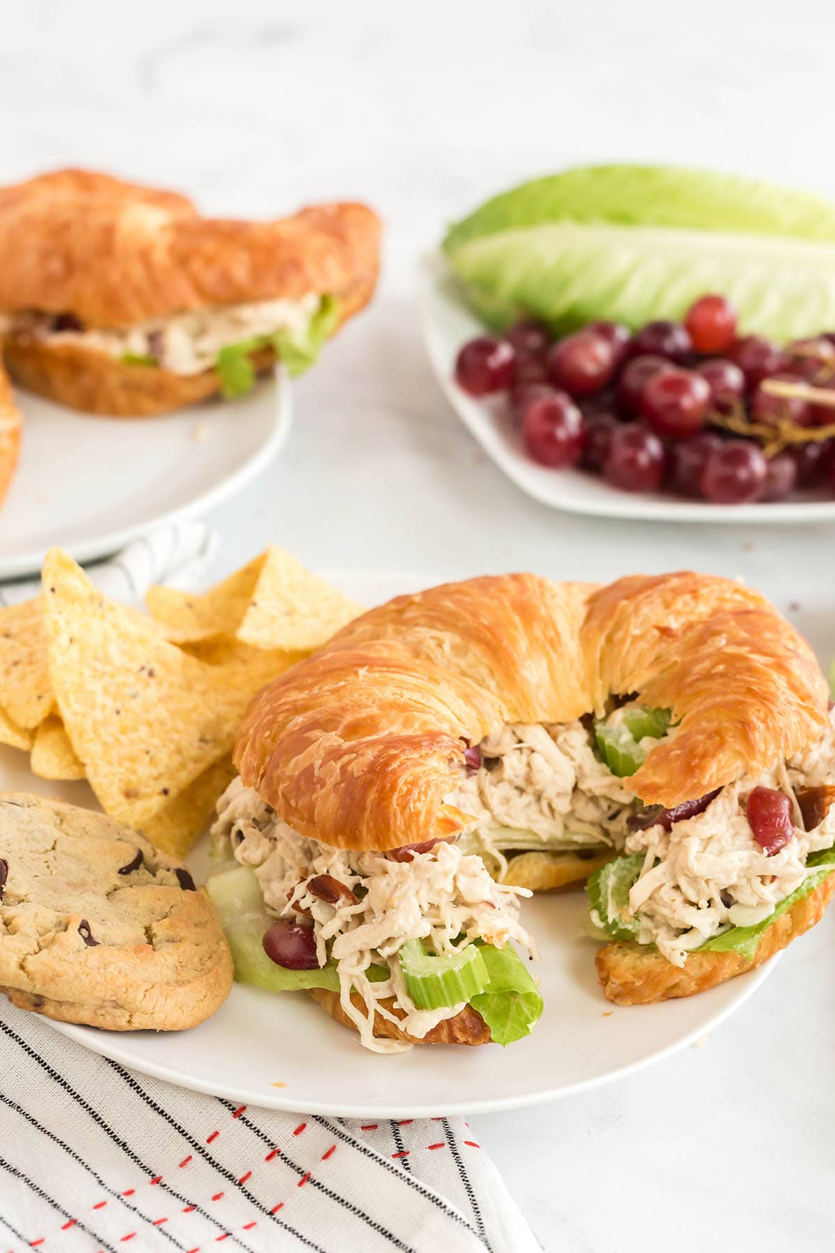 Chicken Salad Sandwiches on a white plate and grapes at the back.