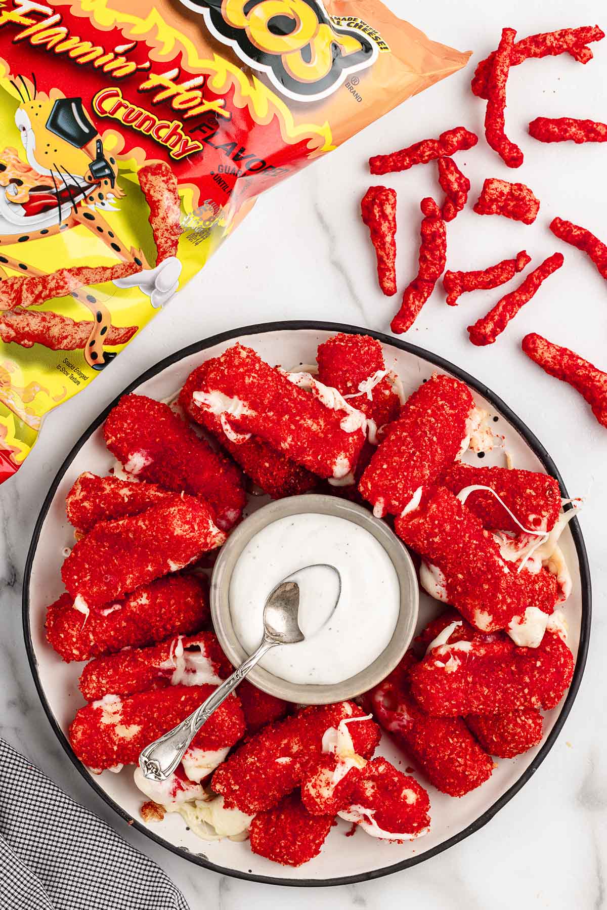 a couple of Hot Cheeto Cheese Sticks on the table with a bowl of dip in the center.