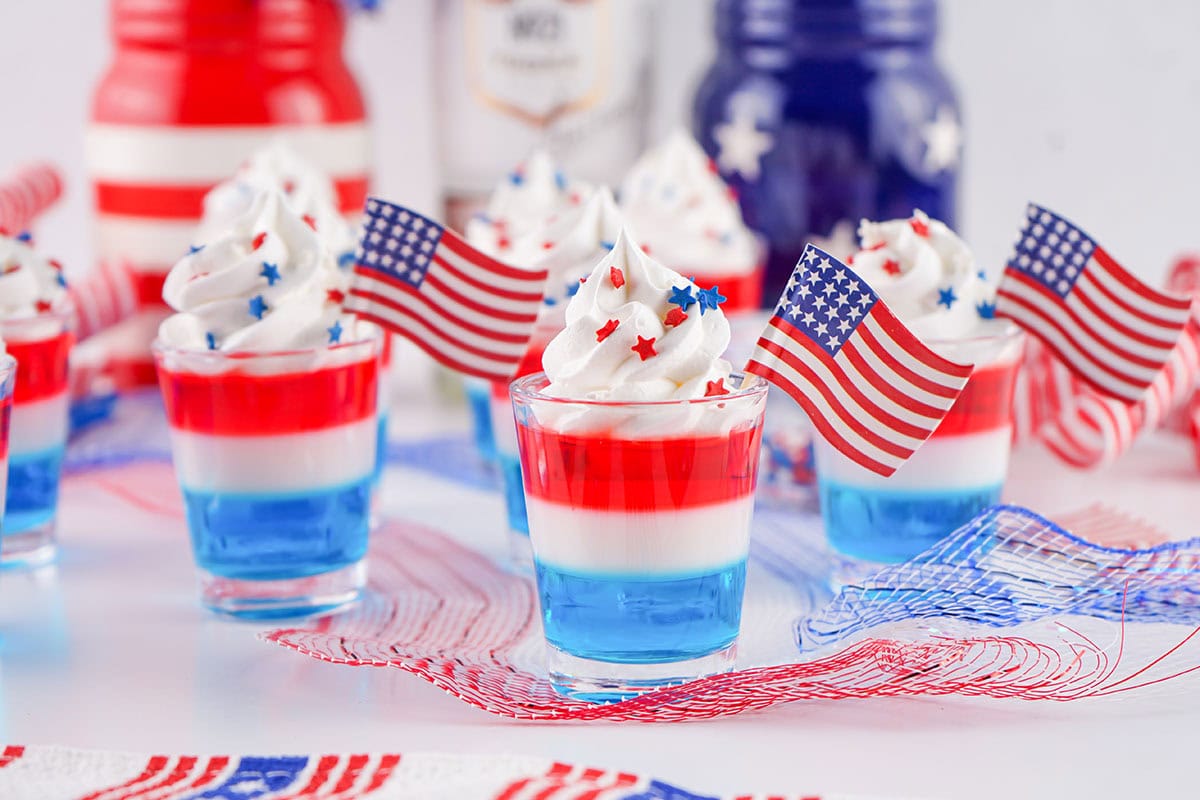 glasses of Red White Blue Jello Shots with toppings and flag.