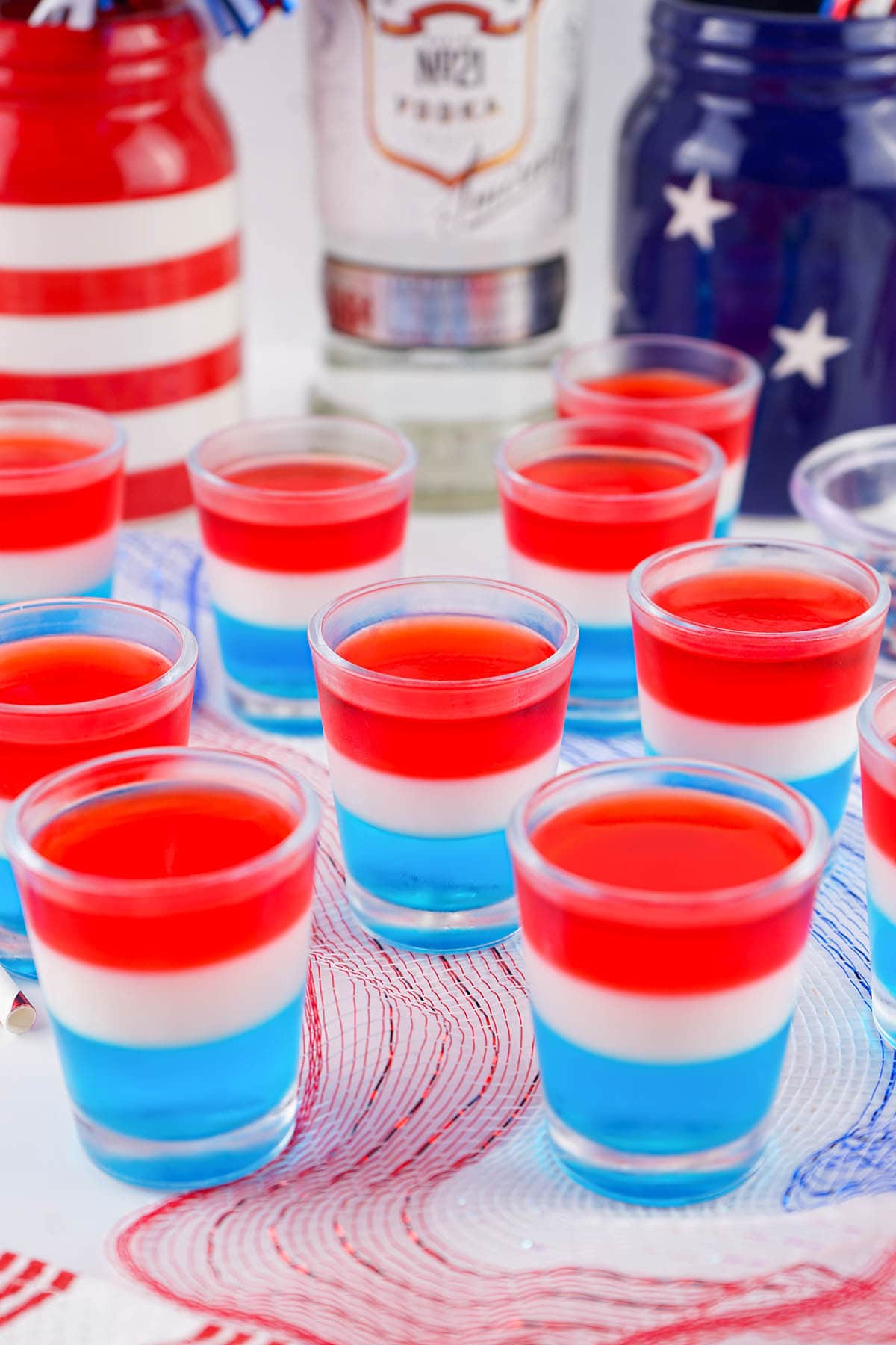 a couple glasses of Red White Blue Jello Shots on the table without toppings.