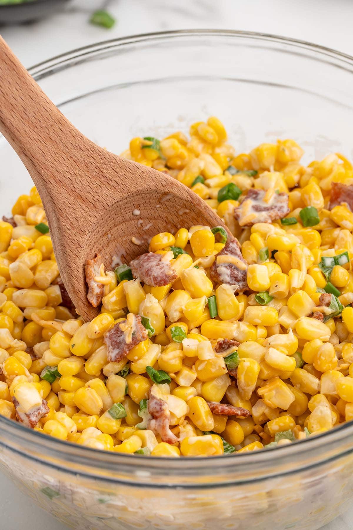 a bowl of Crack Corn Salad with a wooden spoon.