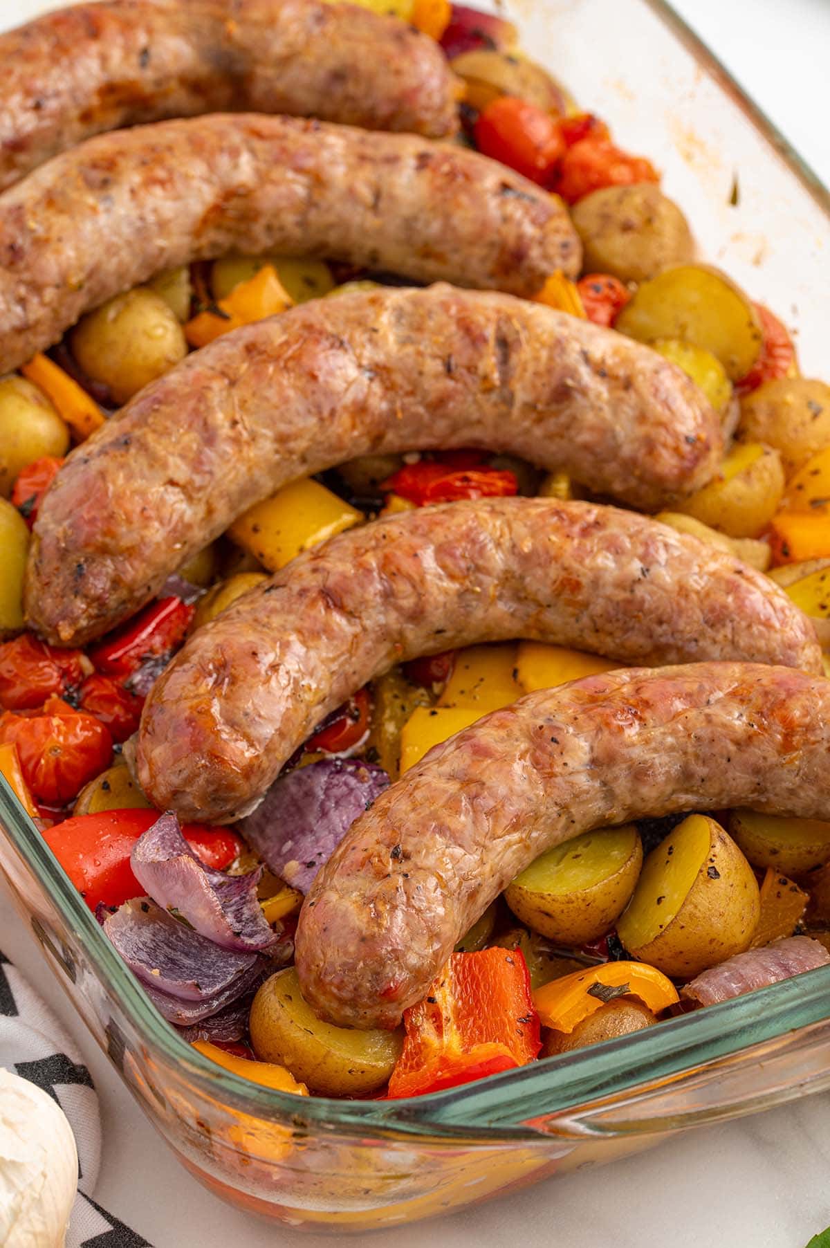 five pieces of baked italian sausages on top of baked vegetables.