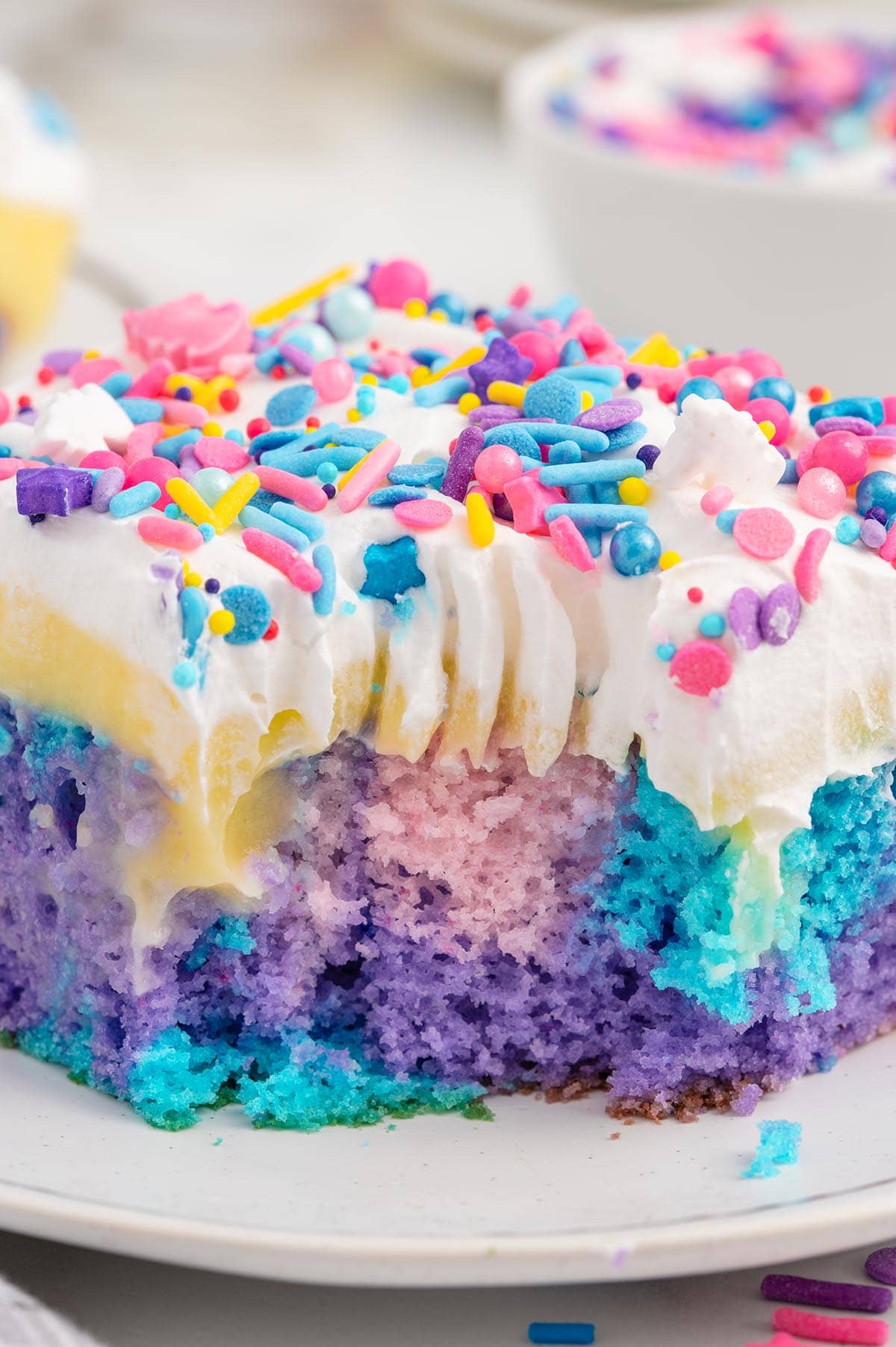 bitten Unicorn Poke Cake on the plate with unicorn candy sprinkles.