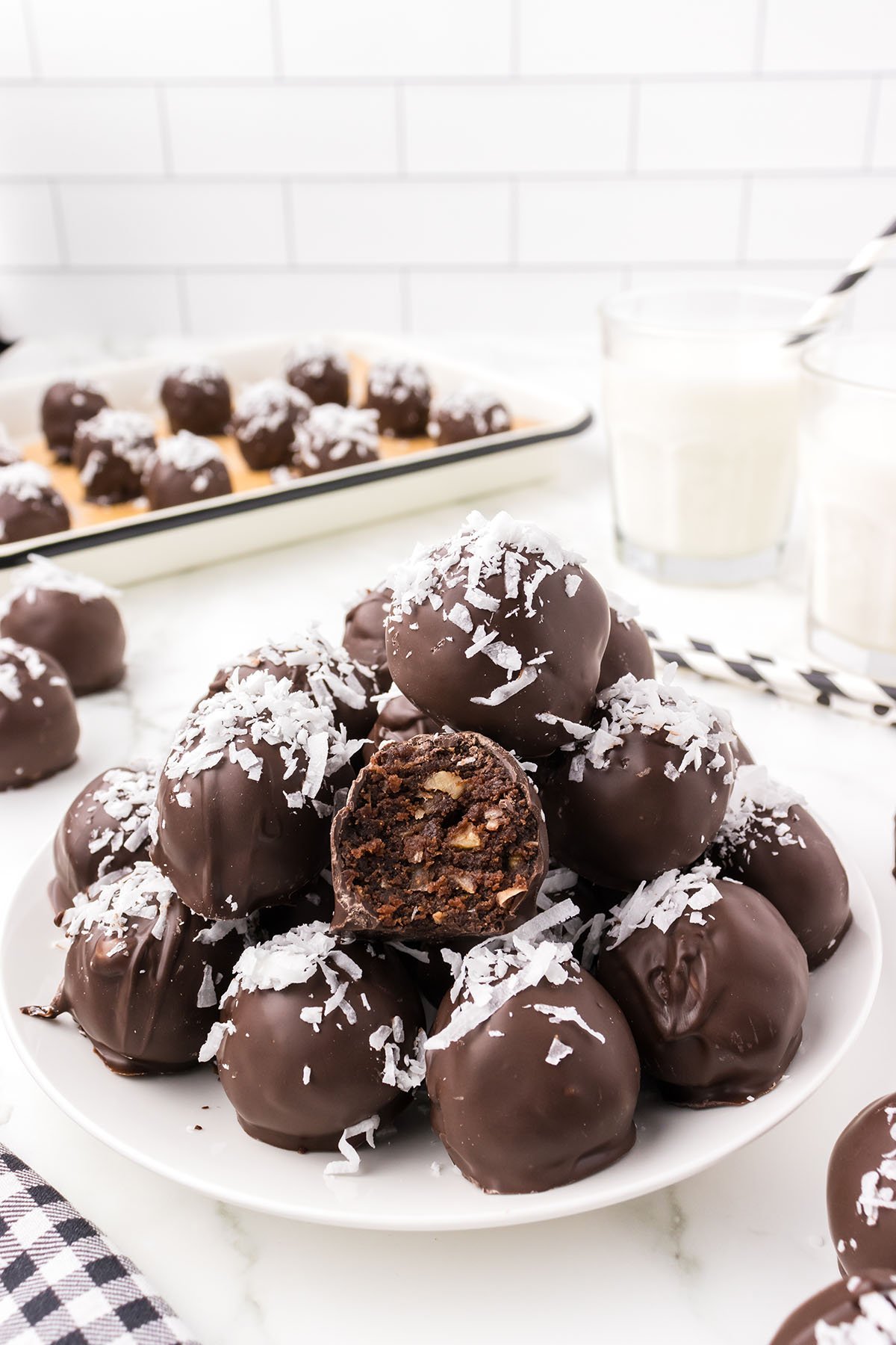 a couple of German Chocolate Truffles on a plate sprinkled with shredded coconut on top.