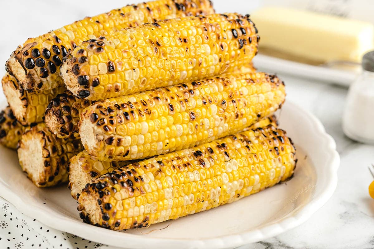a couple of grilled corn on the cob served on the plate.