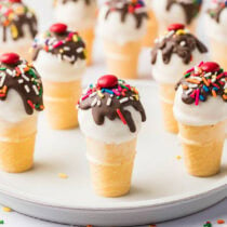 a couple of Cake Pops Ice Cream Cones topped with melted chocolate, sprinkles and M&M's.