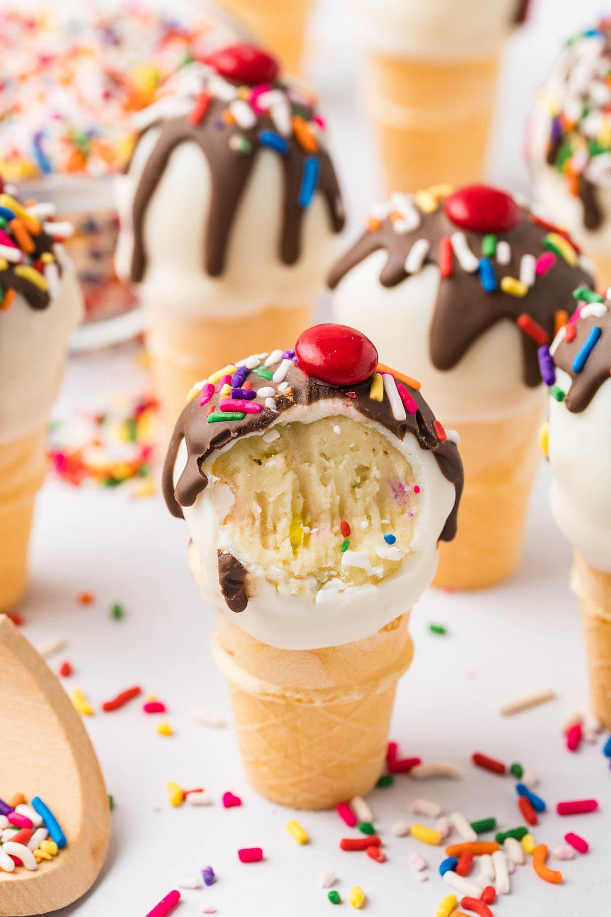 Bitten Cake Pops Ice Cream Cones topped with chocolate, sprinkles and M&M's.