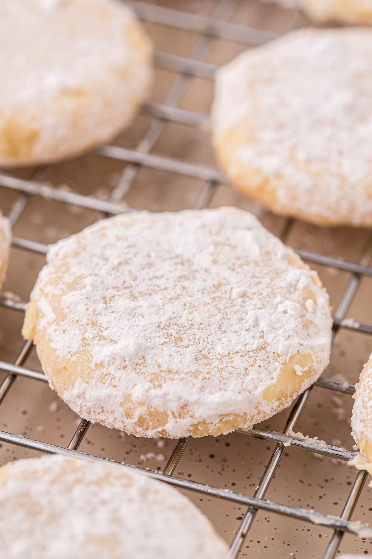 a powdered sugar-covered Lemon Cookies on a cooling rack.