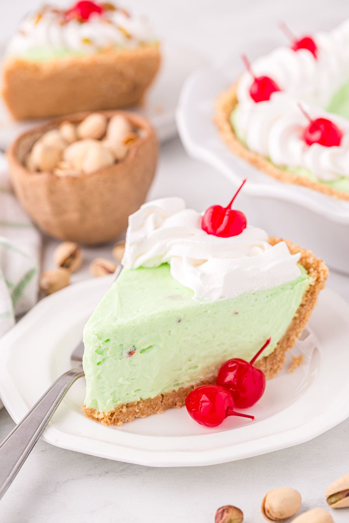 a slice of Pistachio Pie on a white plate with cherry on top.