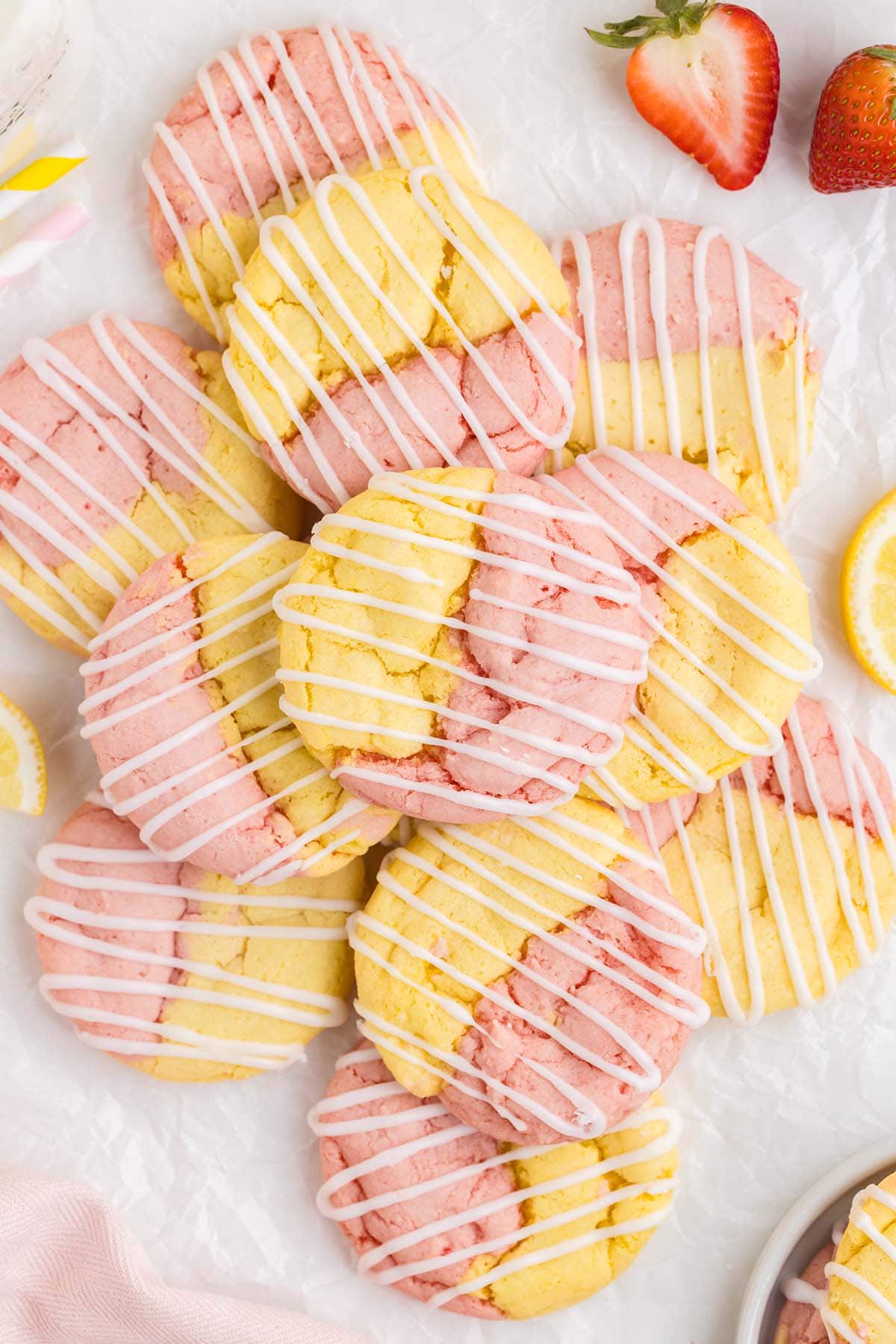 a pile of Strawberry Shortcake Cake Mix Cookies on a white surface drizzled with glaze.