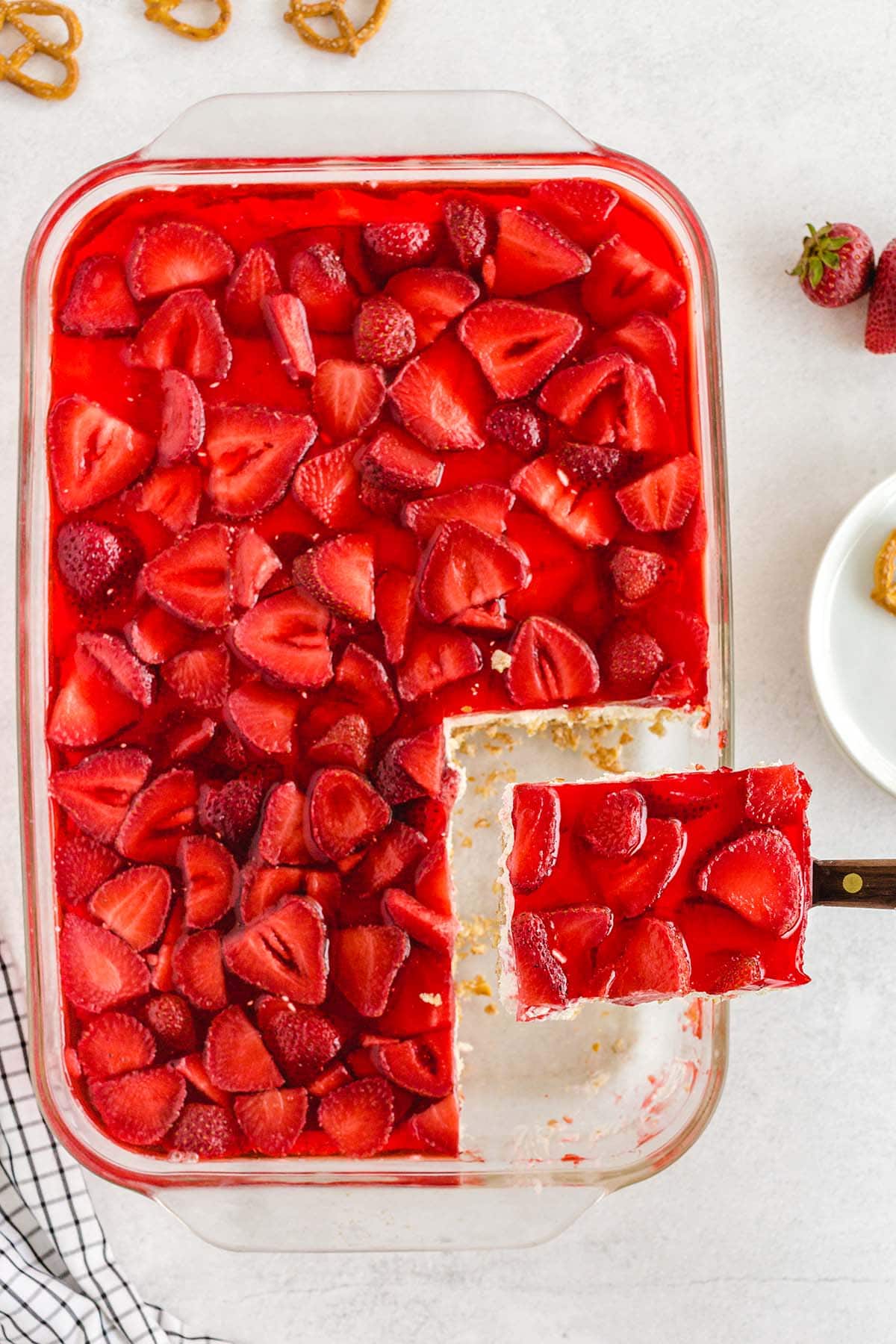 taking out a slice of strawberry pretzel salad from casserole dish. 