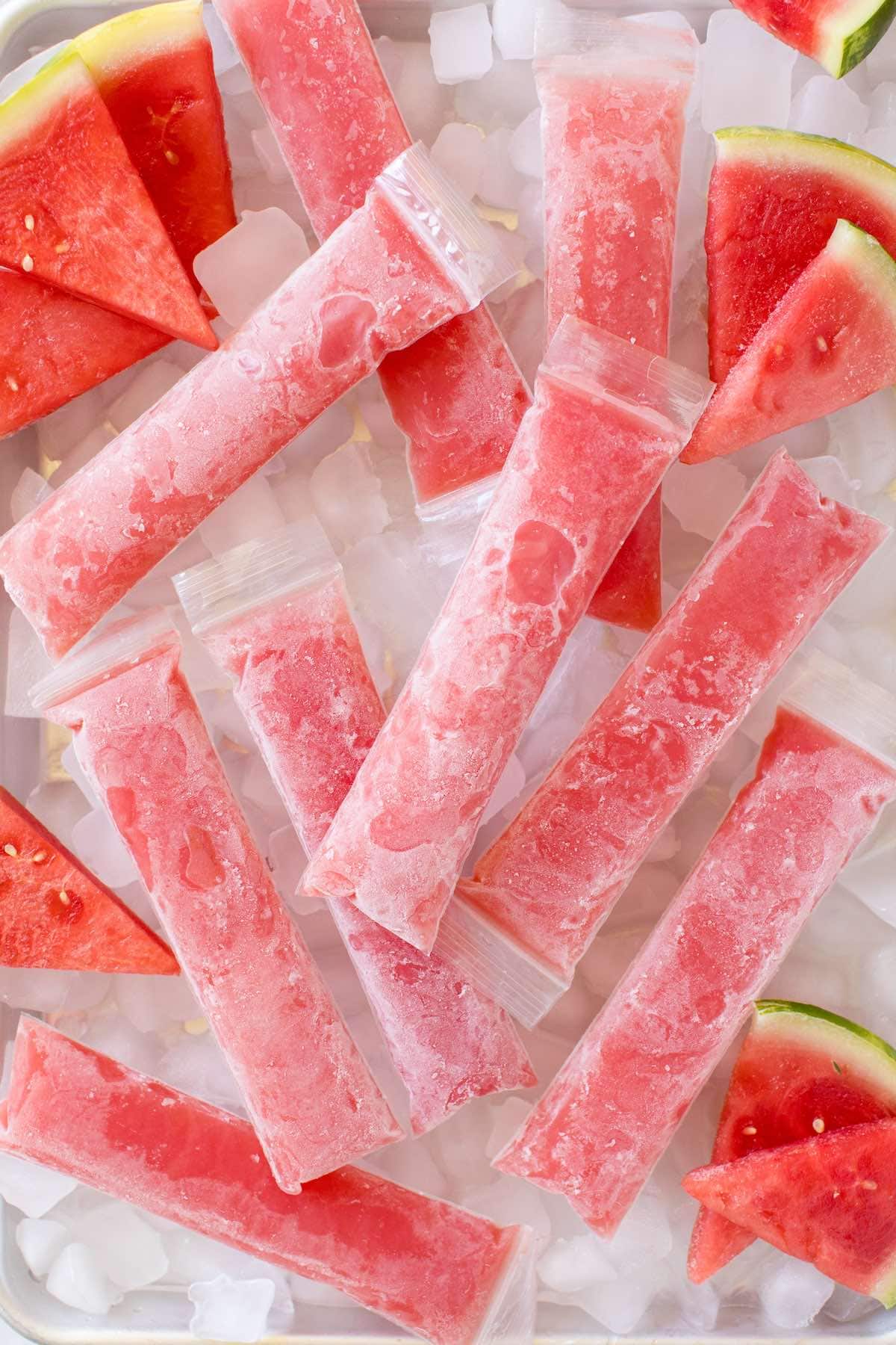 a couple watermelon popsicle on top of tray filled with ice. 