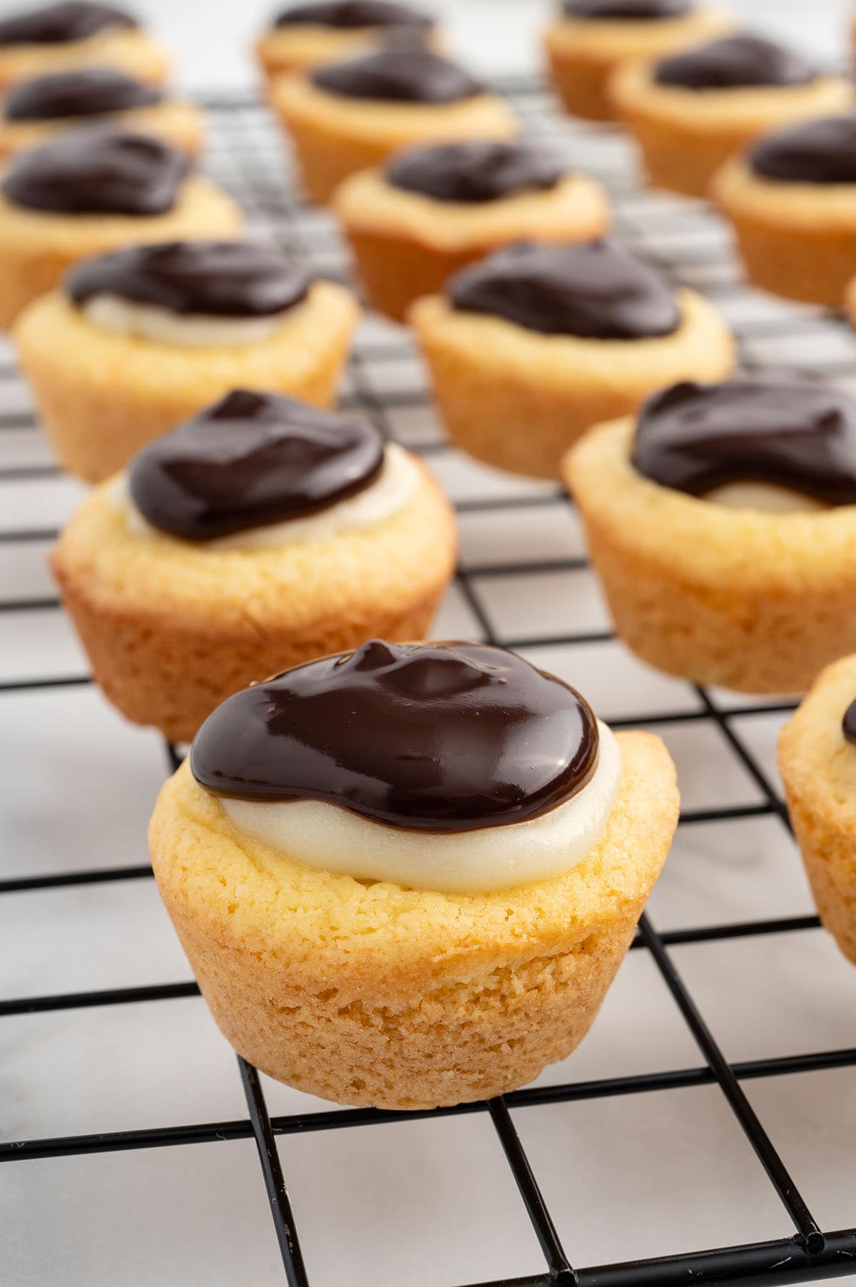 a couple of Boston Cream Pie Cookie Cups on a cooling rack.