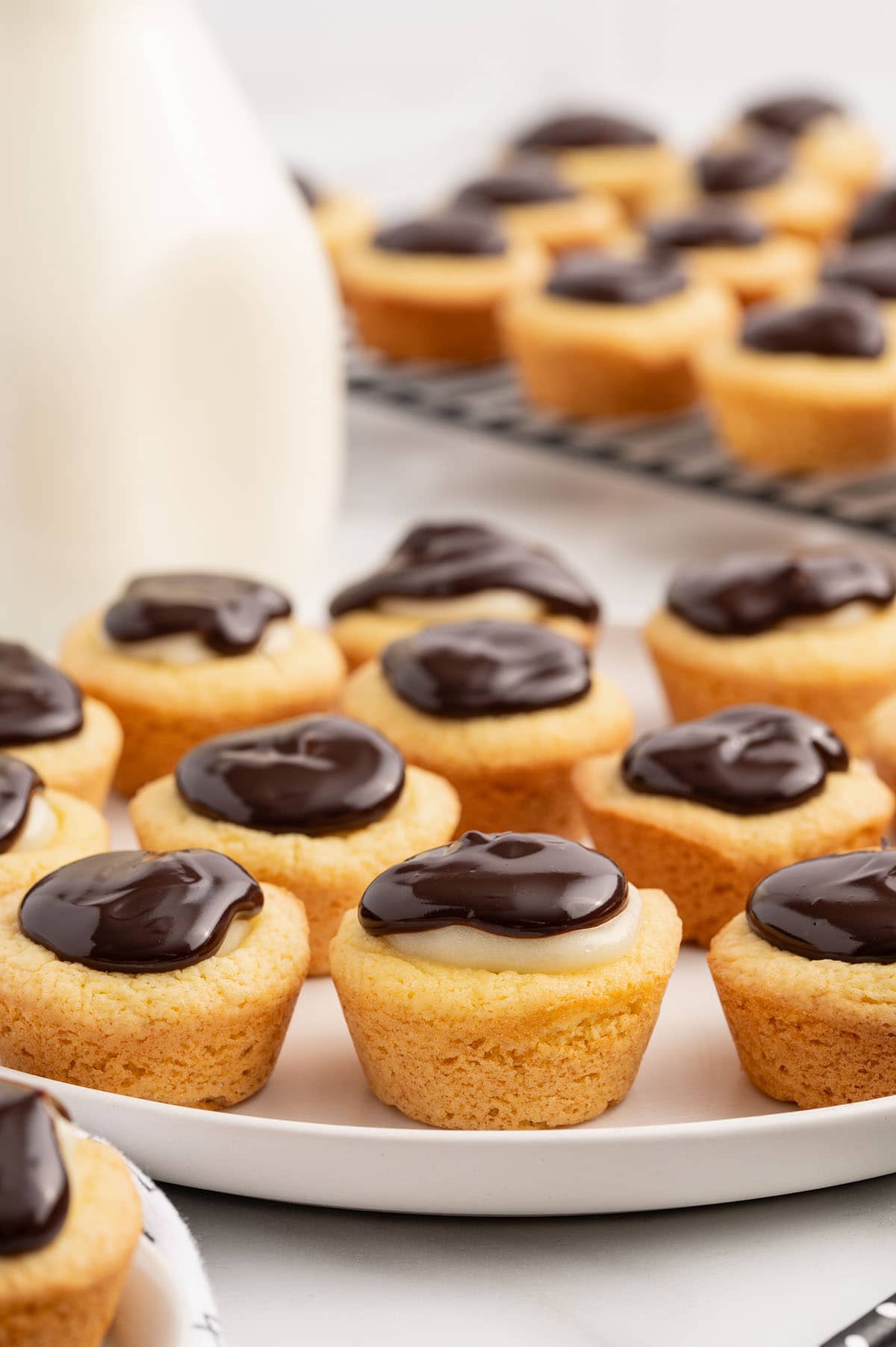 a couple of Boston Cream Pie Cookie Cups topped with chocolate ganache served on a plate. 