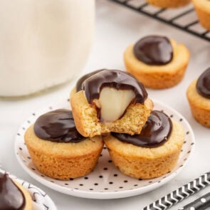 a stack of Boston Cream Pie Cookie Cups on a plate with filling inside and chocolate on top.