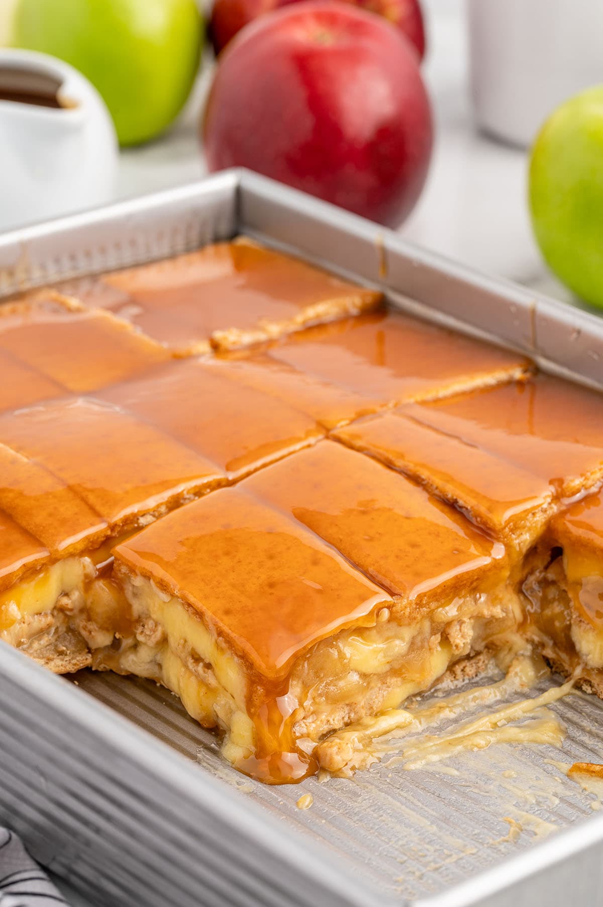 a pan of Caramel Apple Eclair Cake partially sliced into squares.