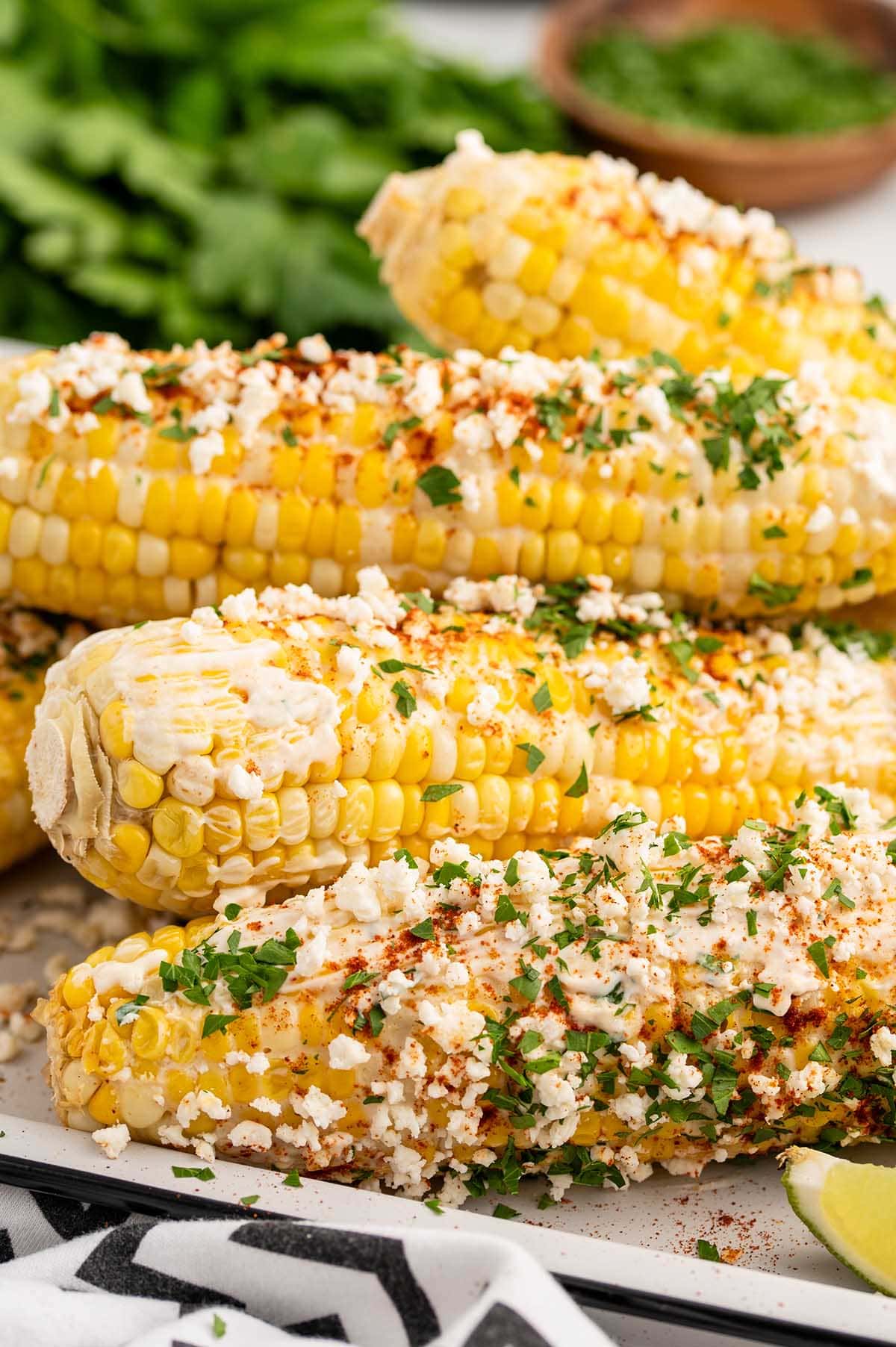 mexican corn on the cob with cotija cheese, chili powder and parsley.