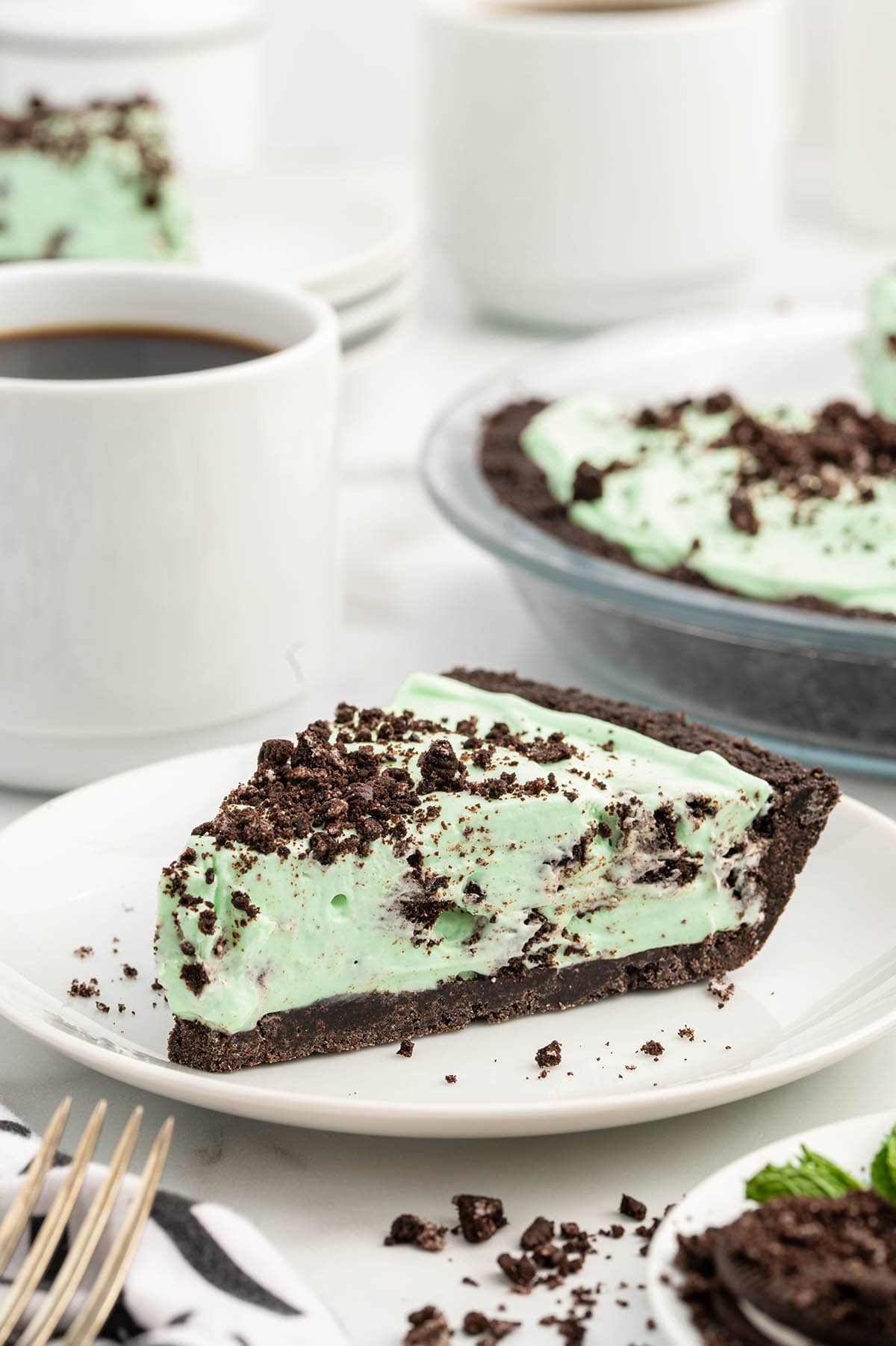 a slice of Mint Chocolate Pie on a white plate garnished with crushed cookies.