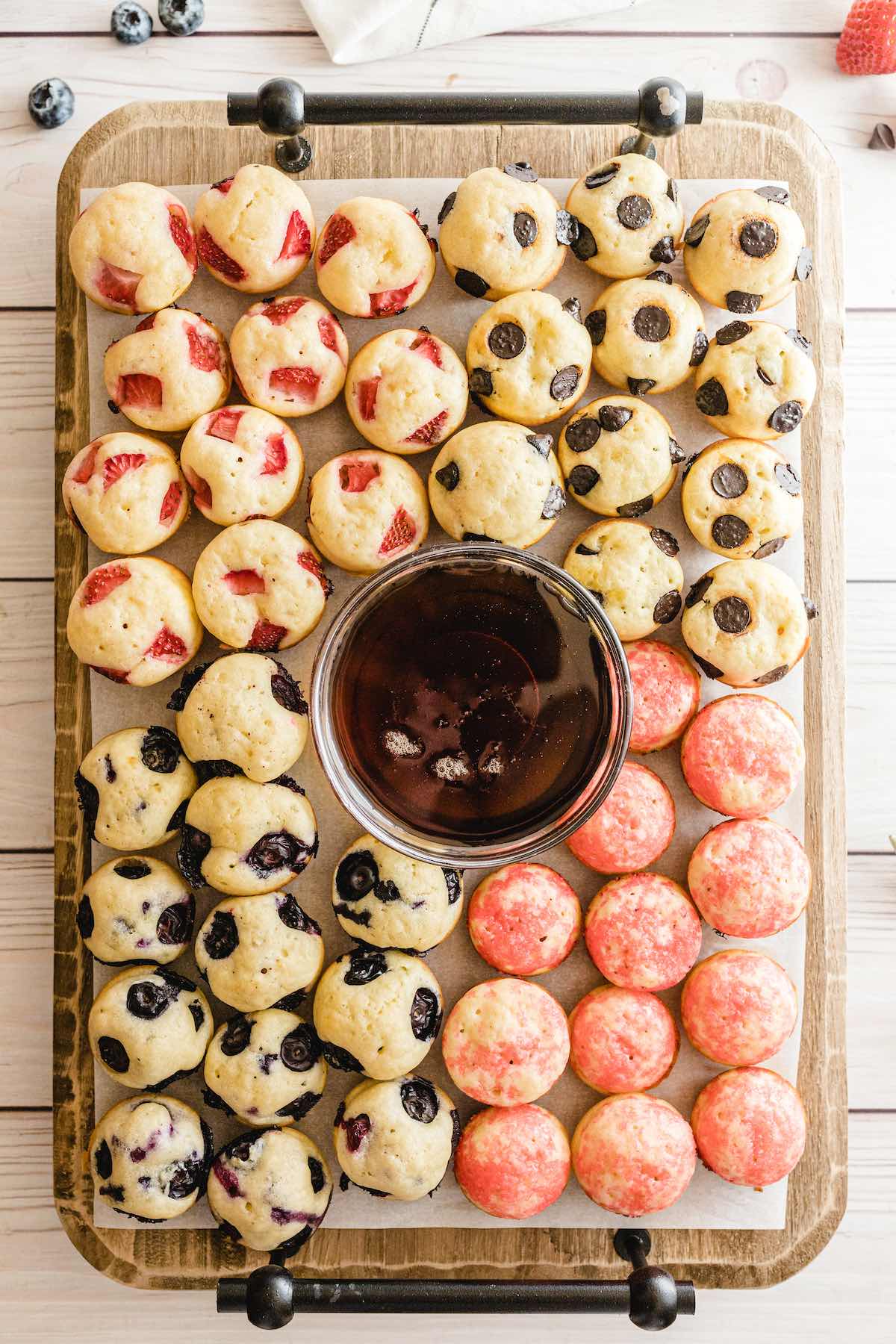 a bunch of mini pancakes on top of wooden tray. 