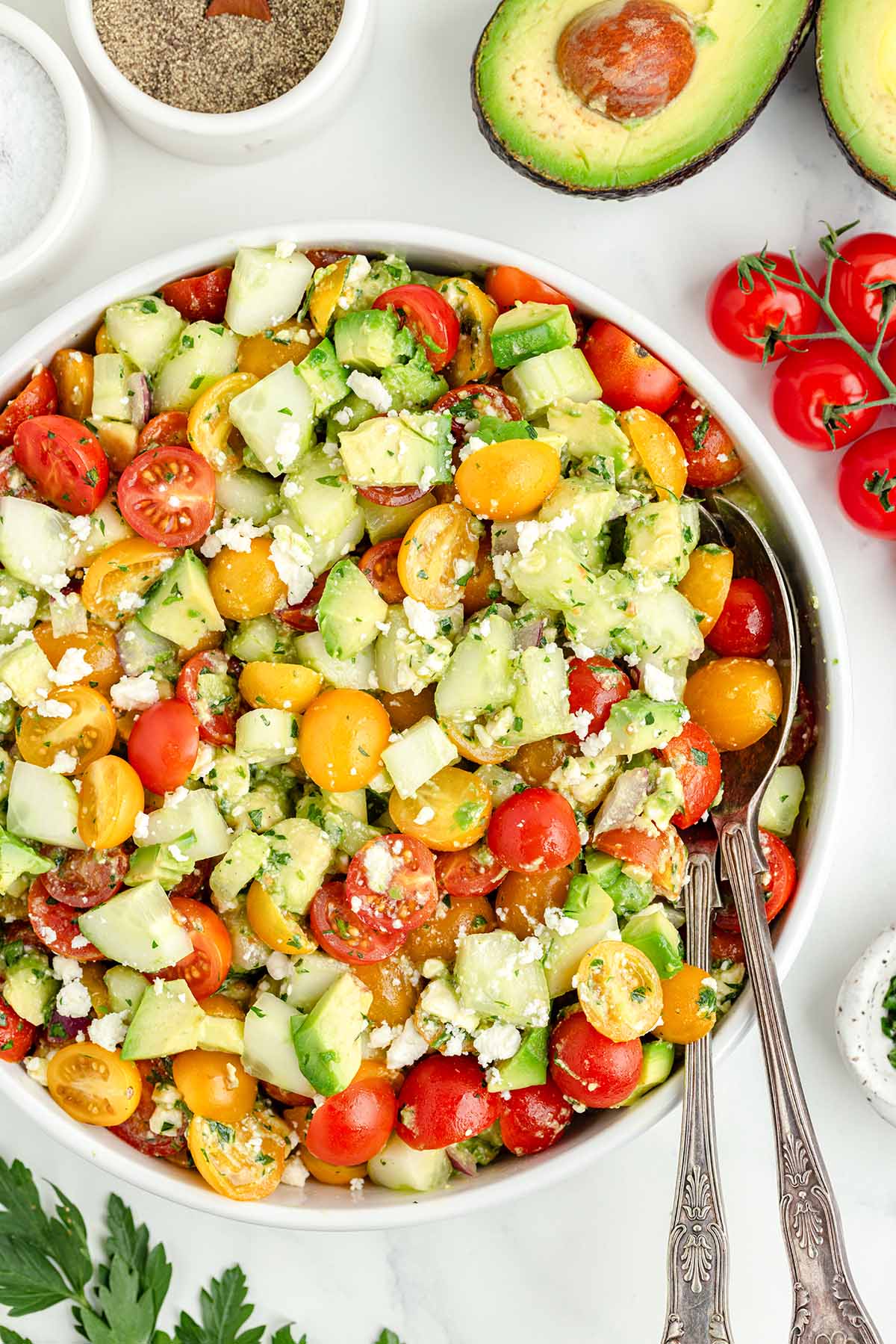 Tomato Cucumber Avocado Salad in a large bowl with serving spoon.