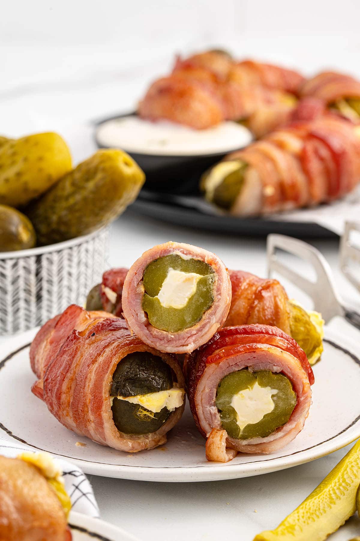 bacon wrapped pickles cut in half and served on a plate. 