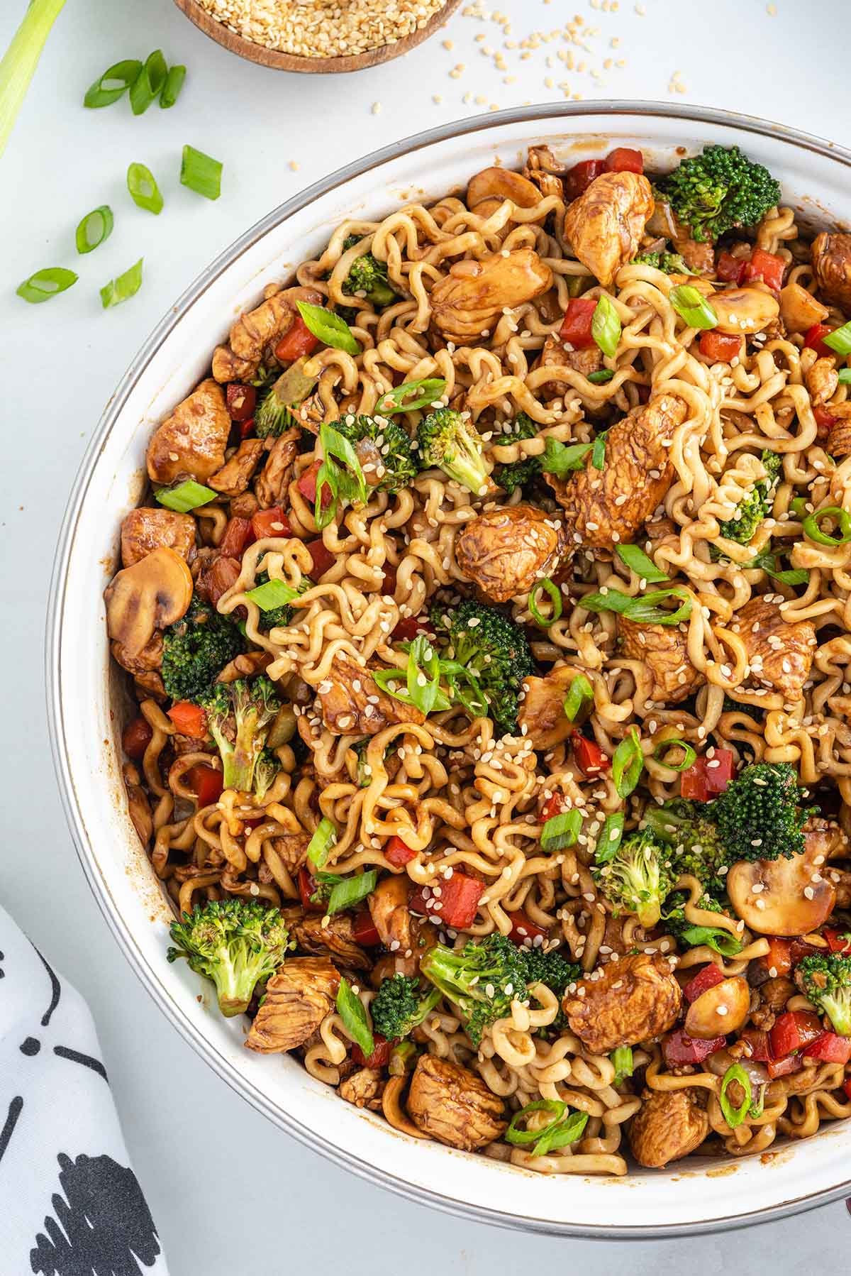 a bowl of Chicken Ramen Stir Fry with vegetables and chicken, garnished with sliced onions and sesame seeds.