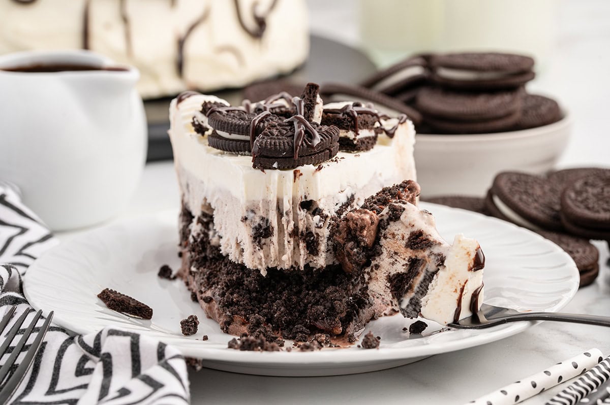 a slice of Dairy Queen Copycat Oreo Cookie Ice Cream Cake garnished with chopped oreos and drizzled with chocolate syrup on top.