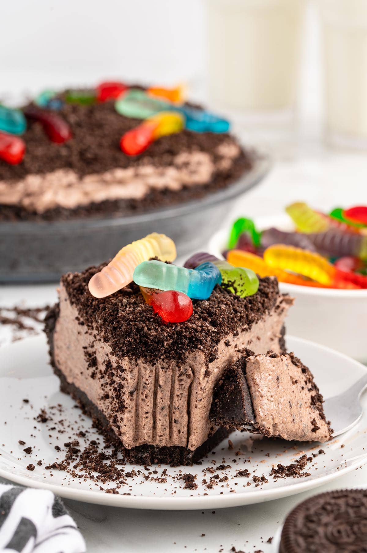 a slice of Dirt Pie with oreo cookie crumbs and colorful gummy worms on top.