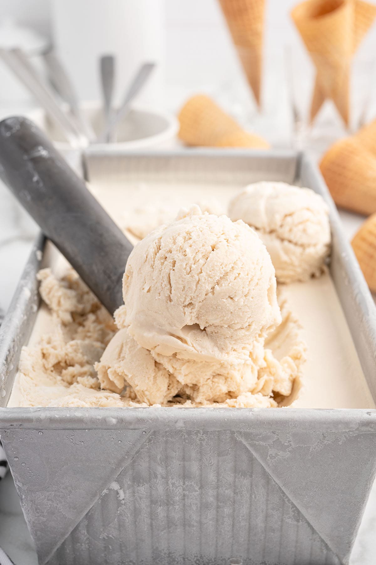 Dr Pepper Ice Cream inside a loaf pan with an ice cream scooper.