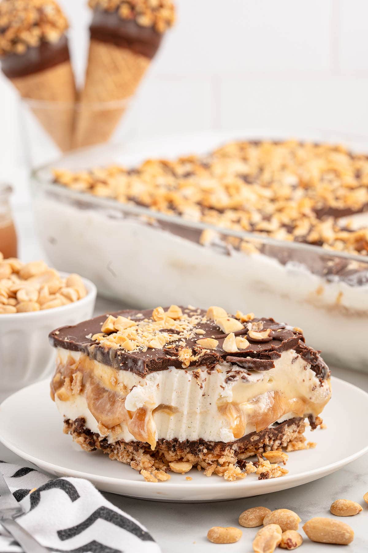 a slice of Drumstick Ice Cream Cake on a white plate topped with chopped nuts.