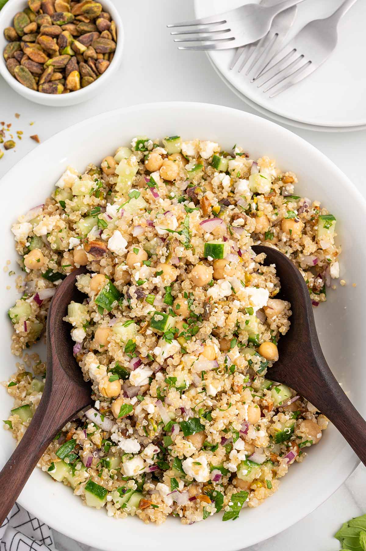 a bowl of Jennifer Aniston Salad garnished with herbs and two wooden spoons.