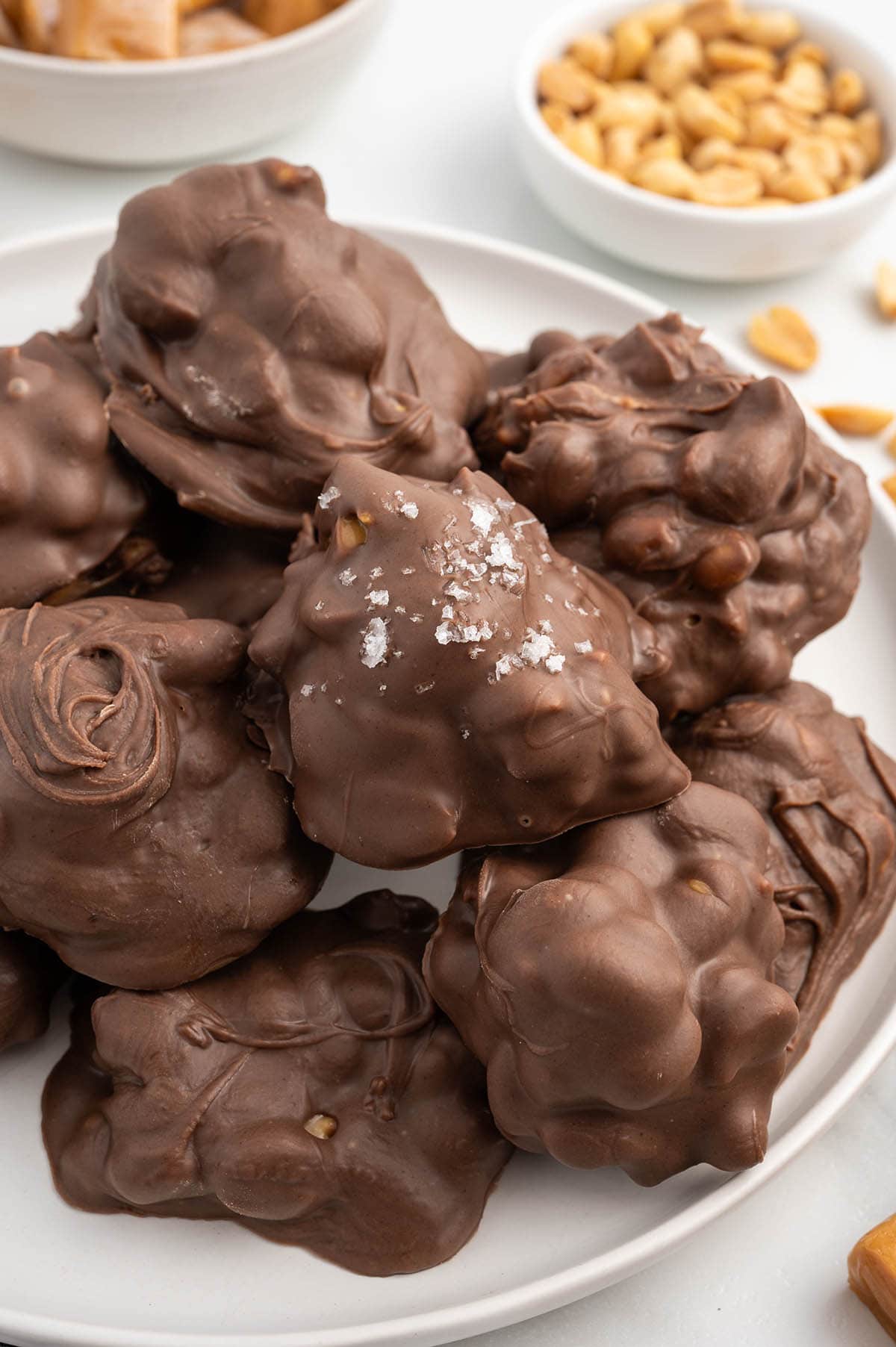 salted peanut caramel clusters stacked on top of white plate. 