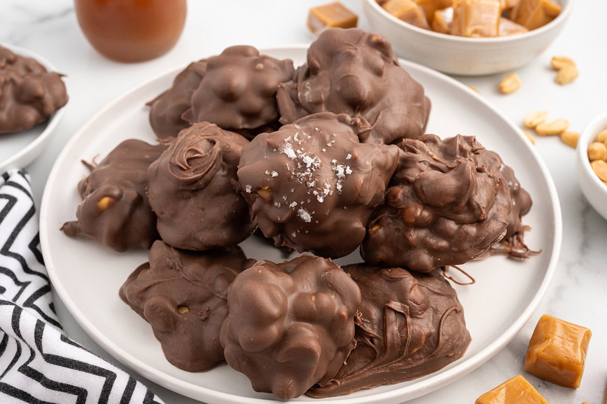 a couple of Salted Peanut Caramel Clusters on a plate and topped with a sprinkle of sea salt.