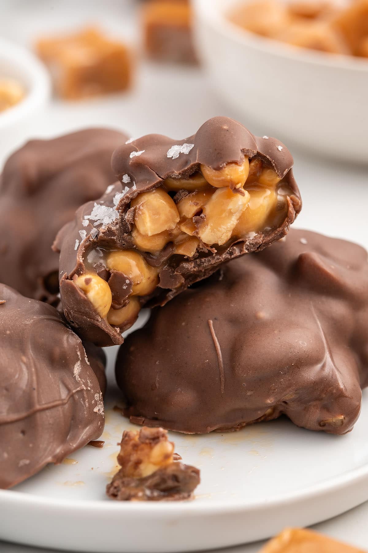 a couple of Salted Peanut Caramel Clusters on a white plate.